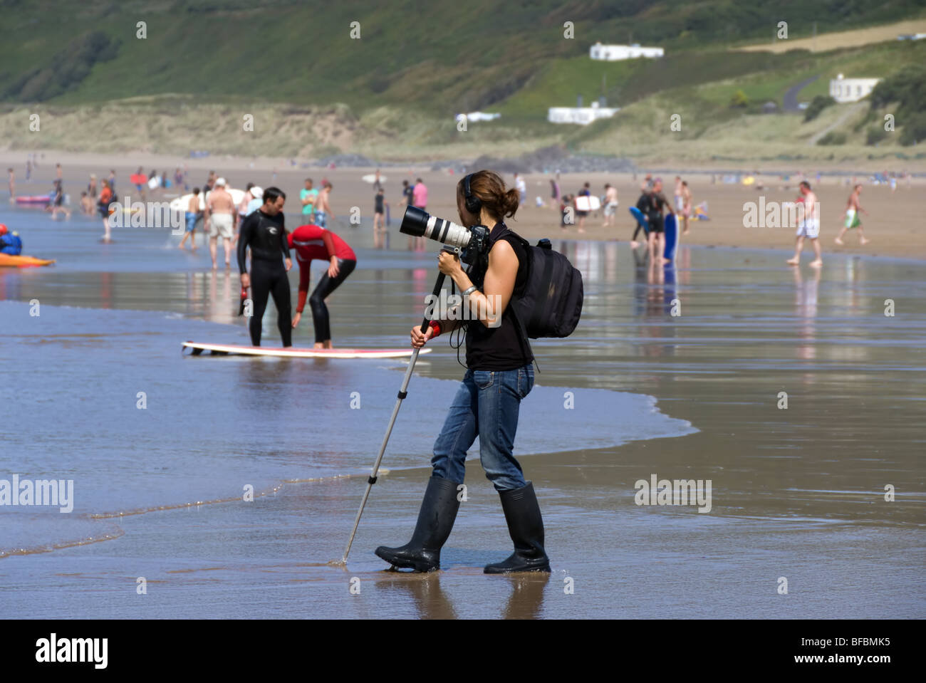 Une jeune femme photographe balade au bord de l'eau sur Puttsborough sands North Devon UK Banque D'Images