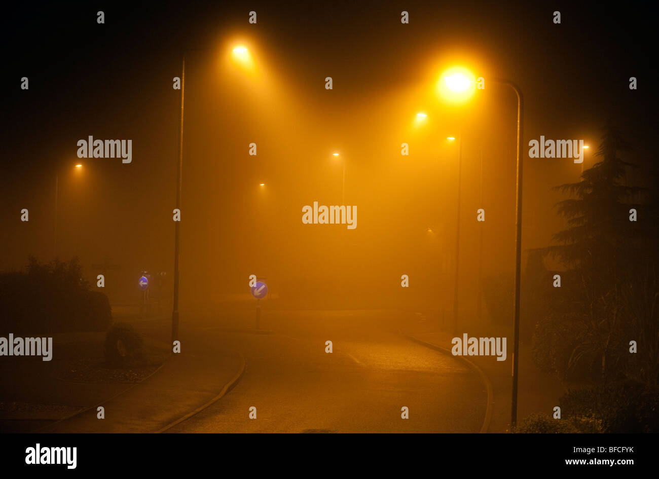 A foggy road avec l'éclairage des rues la nuit à Redditch, Worcestershire, Royaume-Uni Banque D'Images