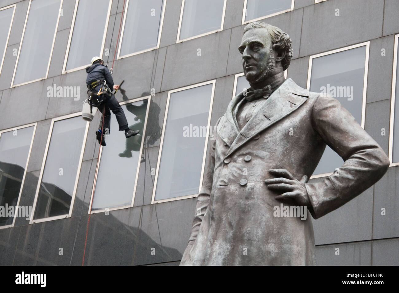 Statue de George Stephenson l'extérieur de la gare de Euston, Londres, avec un nettoyant pour vitres au travail Banque D'Images