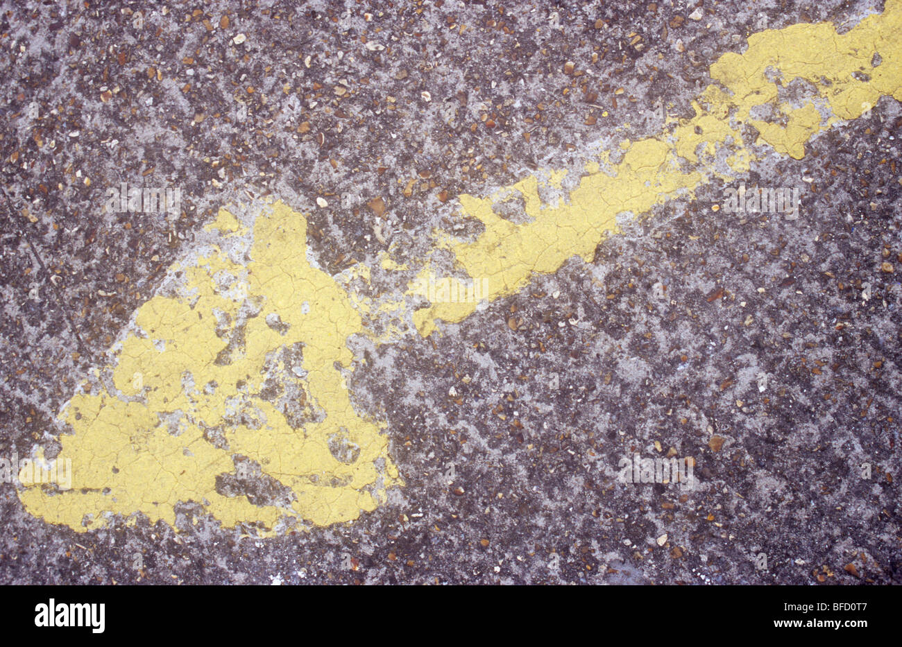 Grande flèche jaune peint sur la surface de béton rugueux mais largement usé par l'usage Banque D'Images