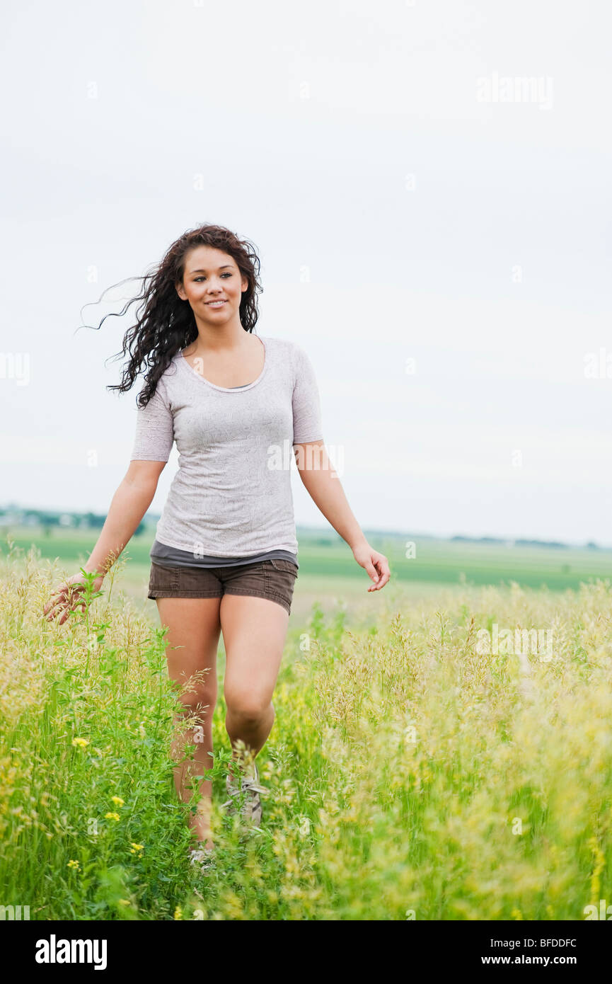 Jeune femme insouciante à pied à travers l'herbe haute sur Spirit of Mound, Dakota du Sud. Banque D'Images