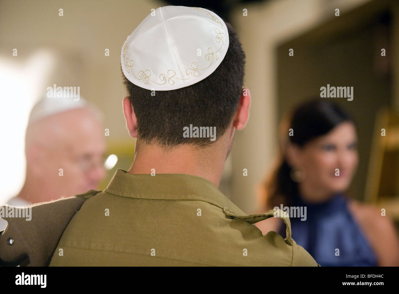 Vue arrière d'un soldat portant une calotte. Famille dans l'arrière-plan. Banque D'Images