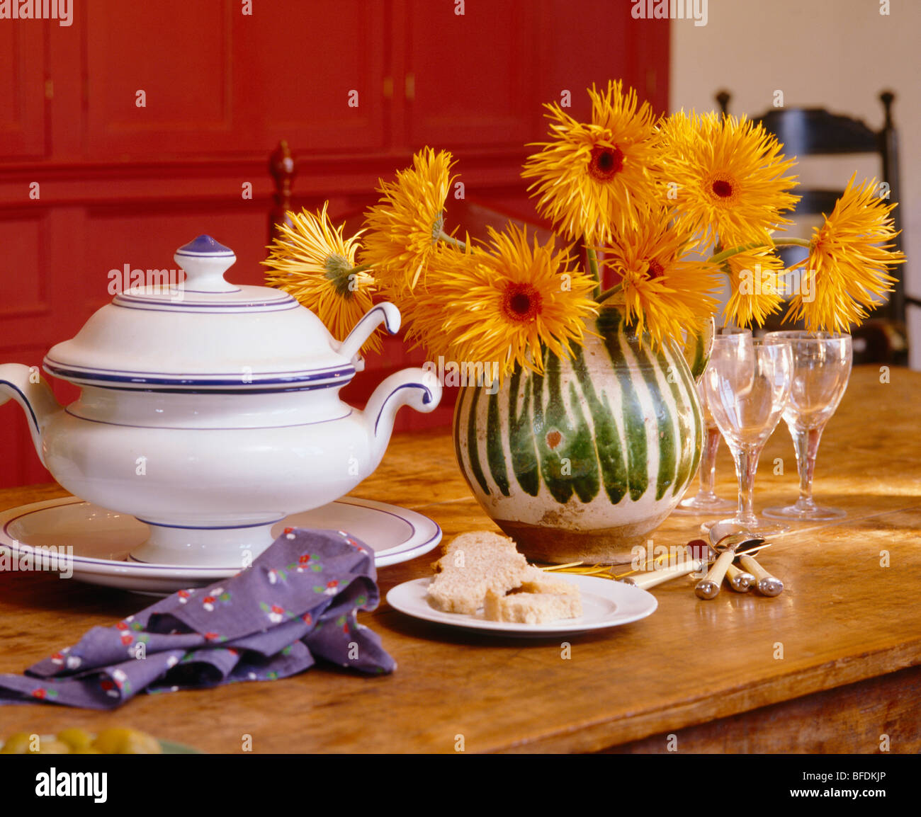Close-up de vase de chrysanthèmes orange à côté de soupière blanche sur table à manger en bois Banque D'Images