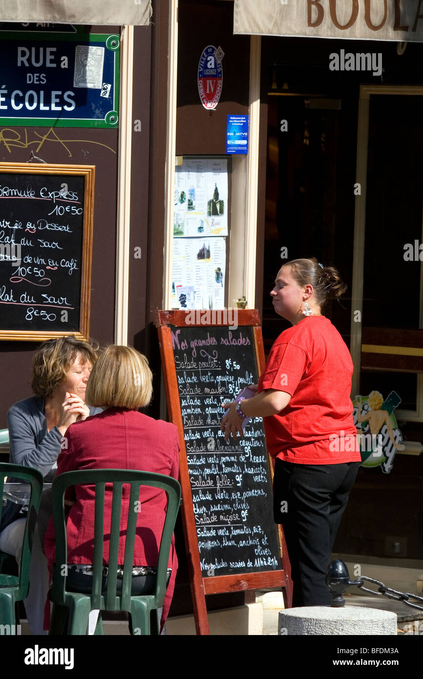 Serveuse accueil des clients dans un café-terrasse à Paris, France. Banque D'Images