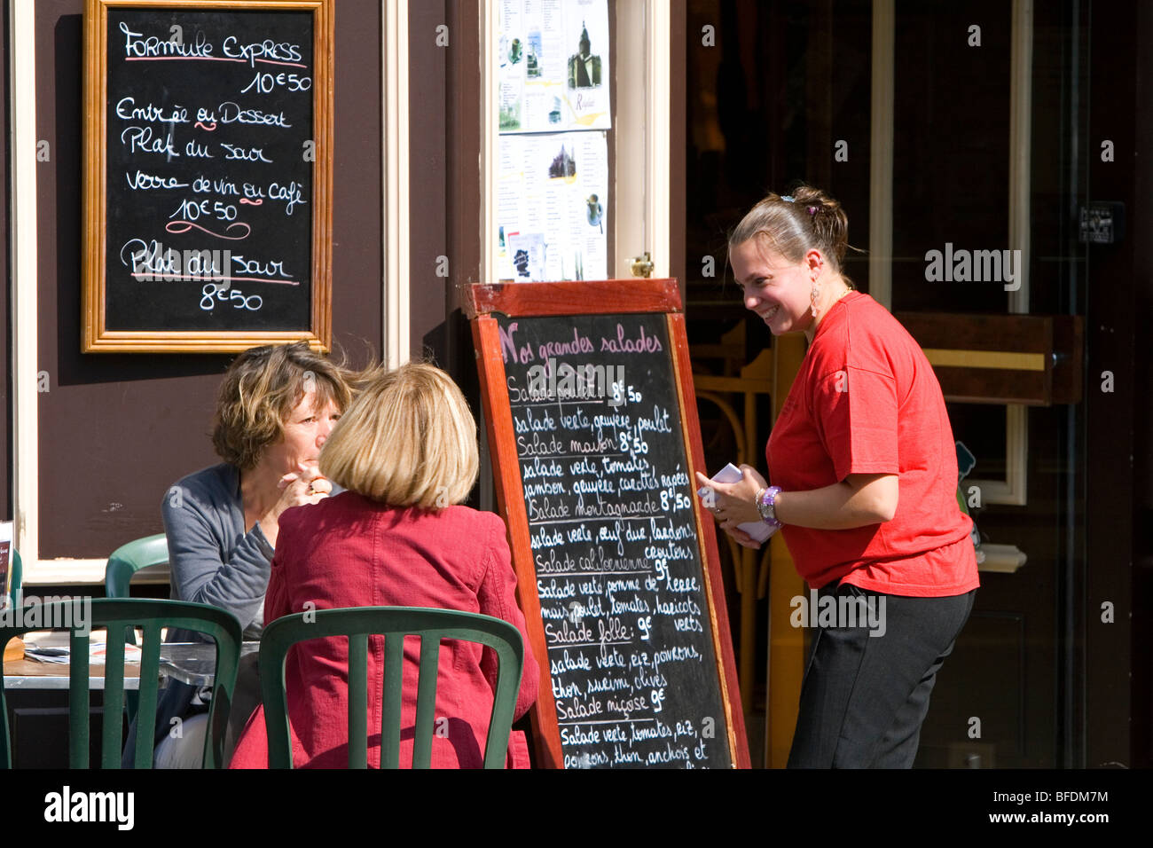 Serveuse accueil des clients dans un café-terrasse à Paris, France. Banque D'Images