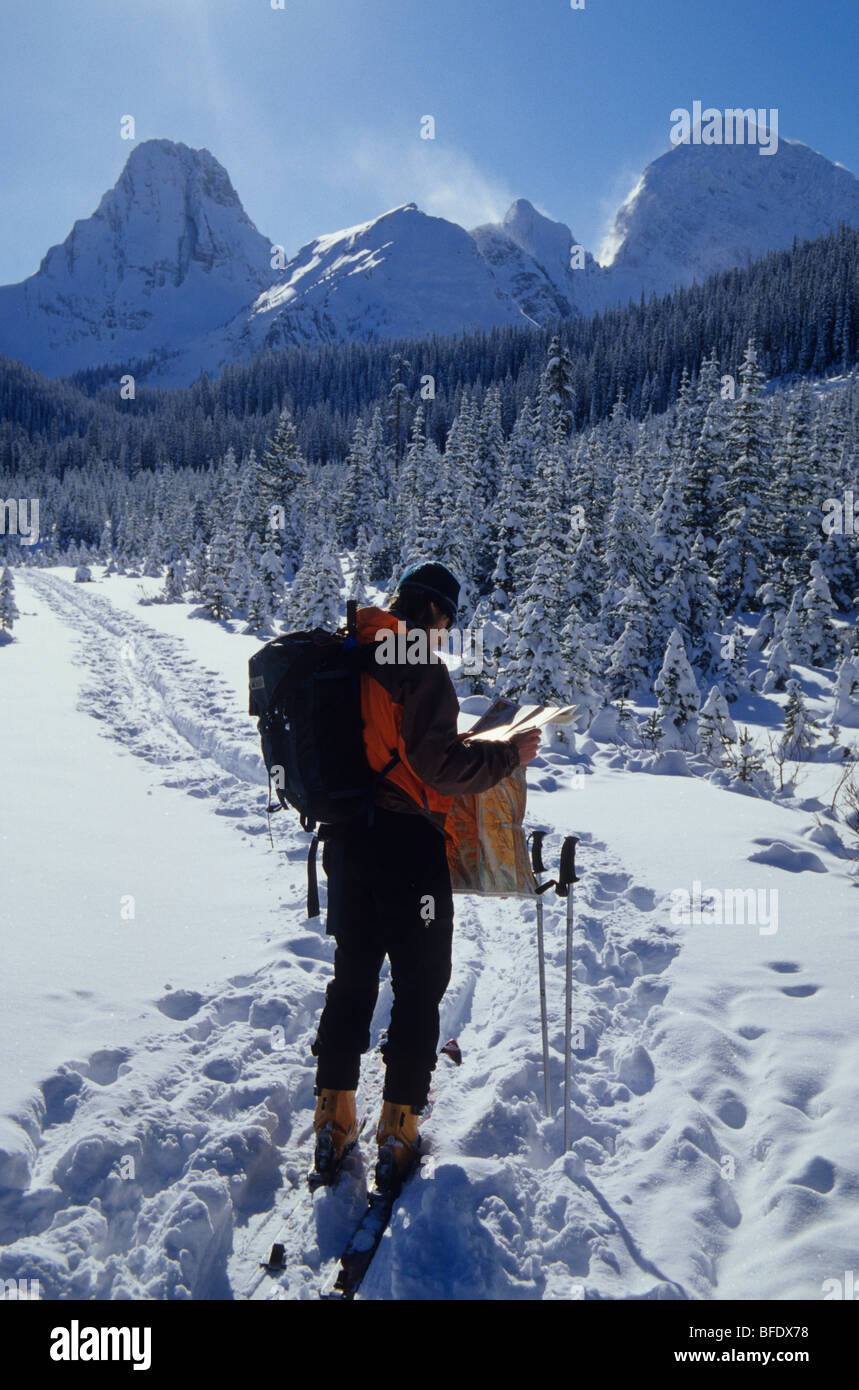 Un skieur de l'arrière-pays vérifie son double roulements dans la région de Kananaskis, montagnes Rocheuses, Alberta, Canada Banque D'Images