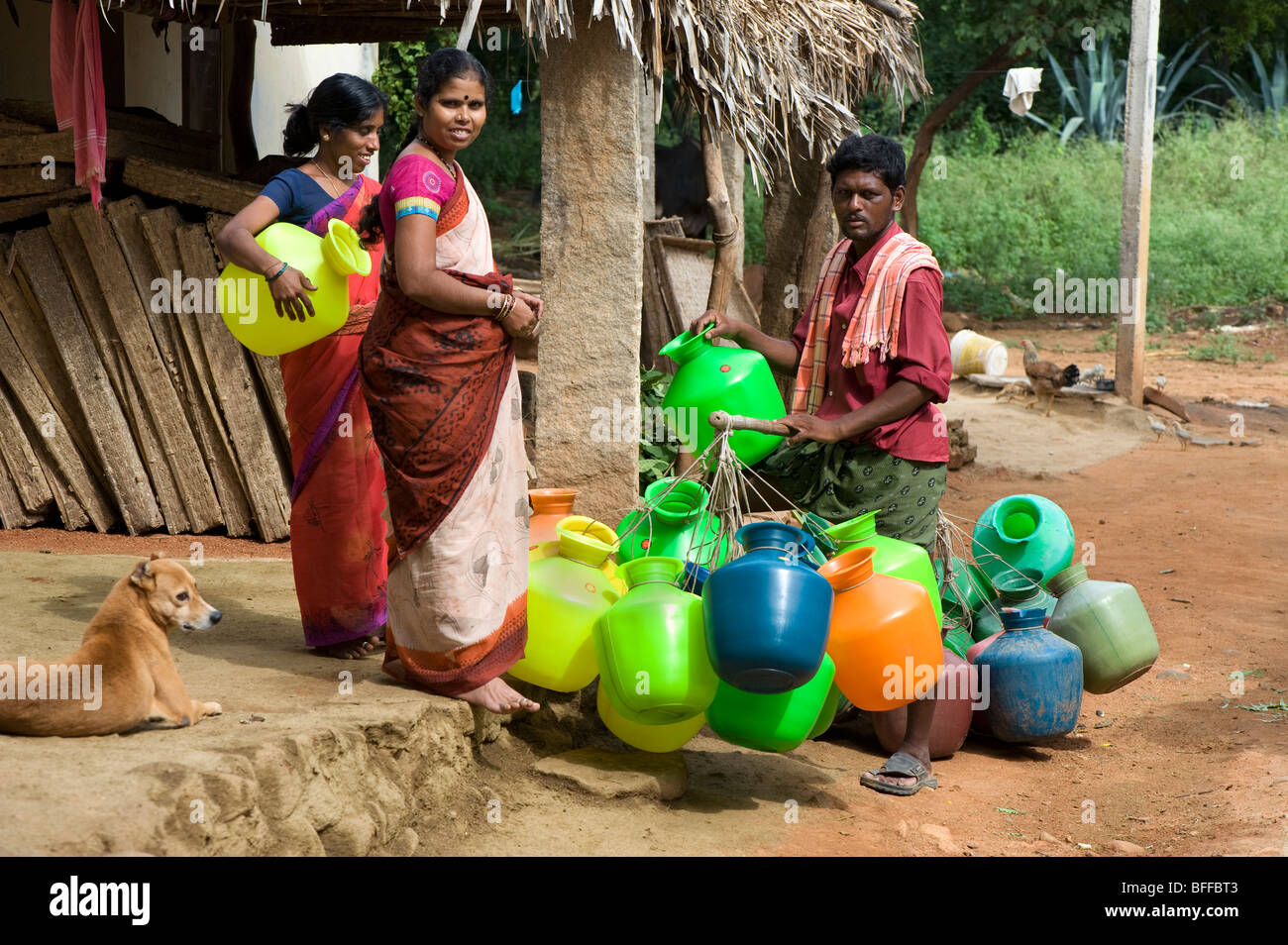 L'homme indien vendant de l'eau plastique pots pour les femmes dans un village de l'Inde rurale. L'Andhra Pradesh, Inde Banque D'Images