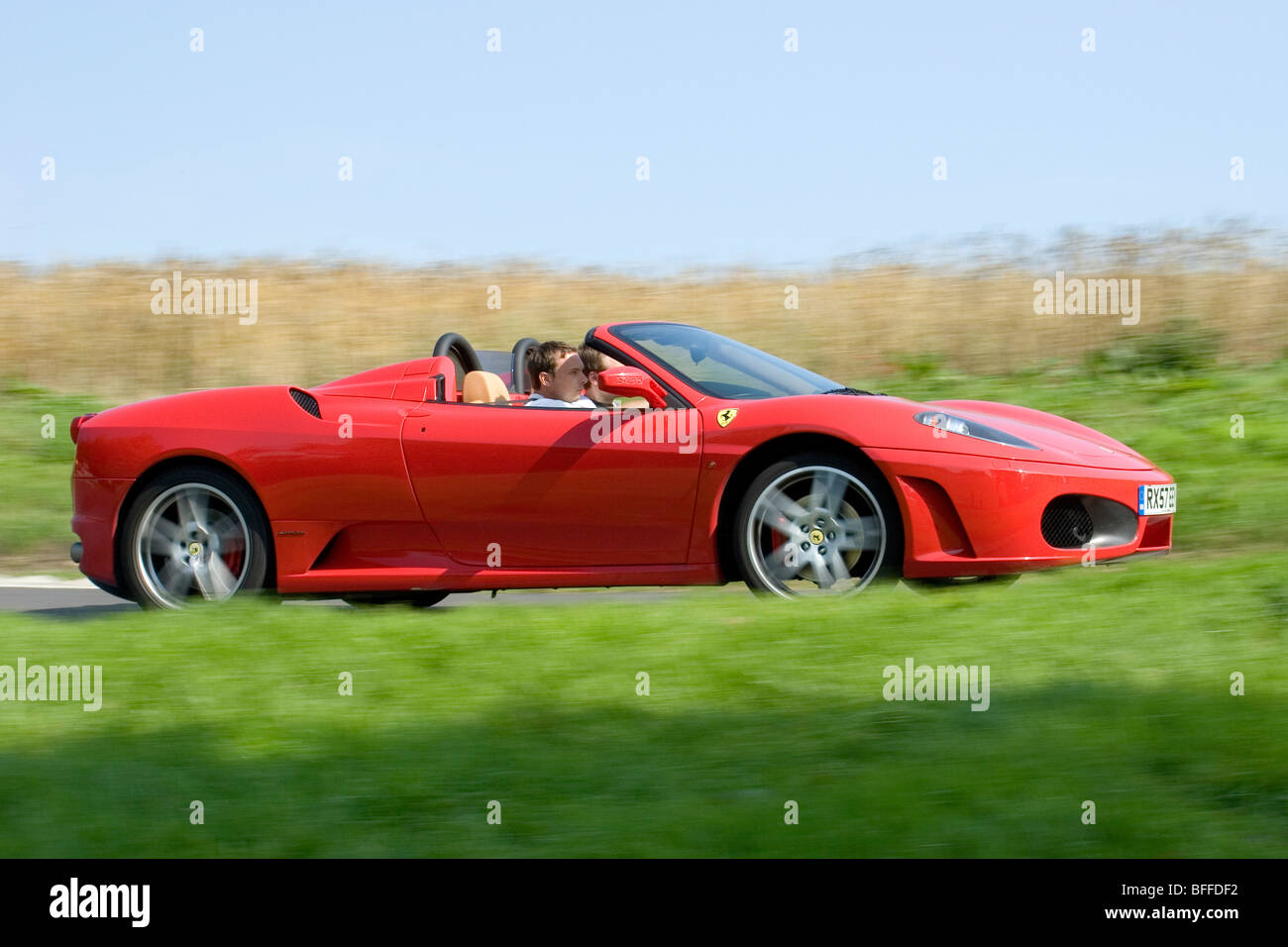 Profil de l'angle faible (vue de côté) d'un rouge Ferrari 360 Spider dans supercar motion sur la voie publique conduite rapide Banque D'Images