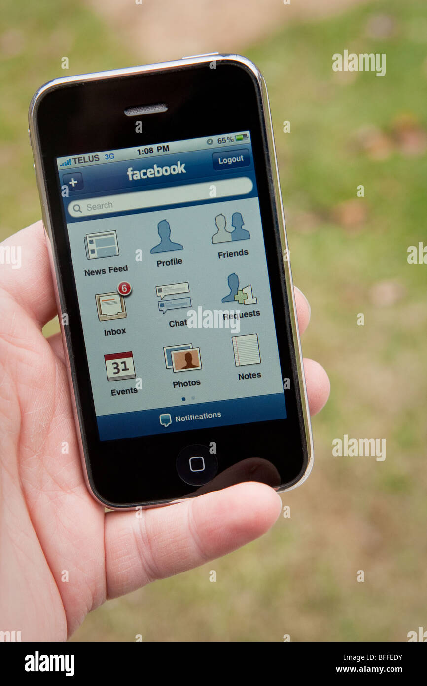 Un homme utilisez l'application Facebook sur un iPhone d'Apple. Banque D'Images