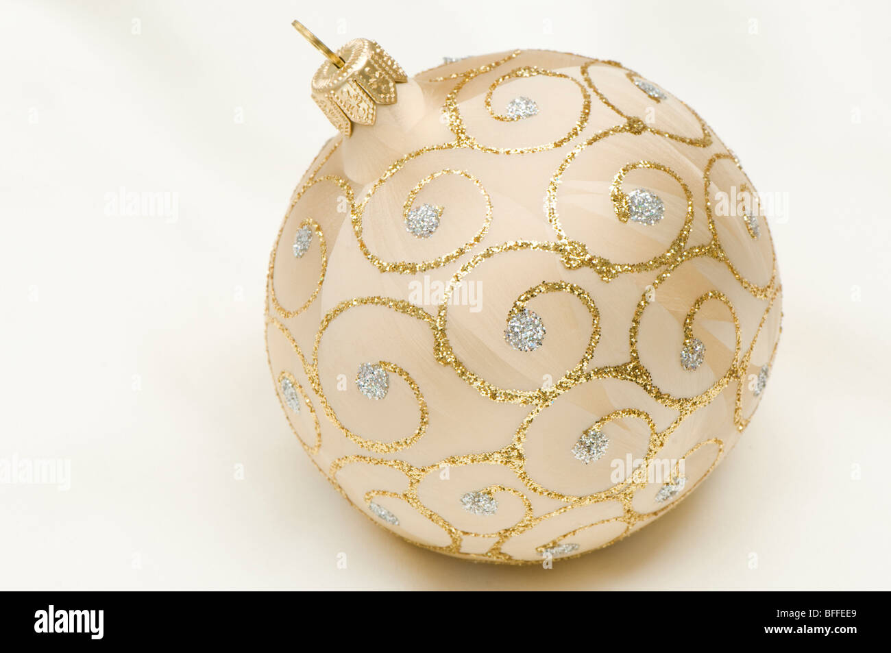 Boule de Noël d'or et d'argent contre un arrière-plan blanc crème Banque D'Images