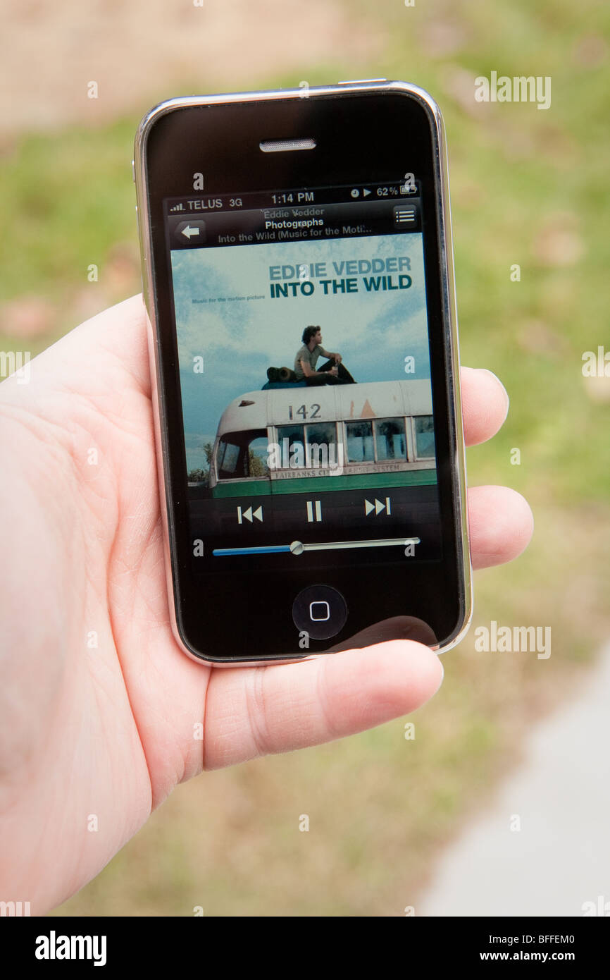 Un homme utiliser l'application MP3 sur un iPhone d'Apple. Banque D'Images