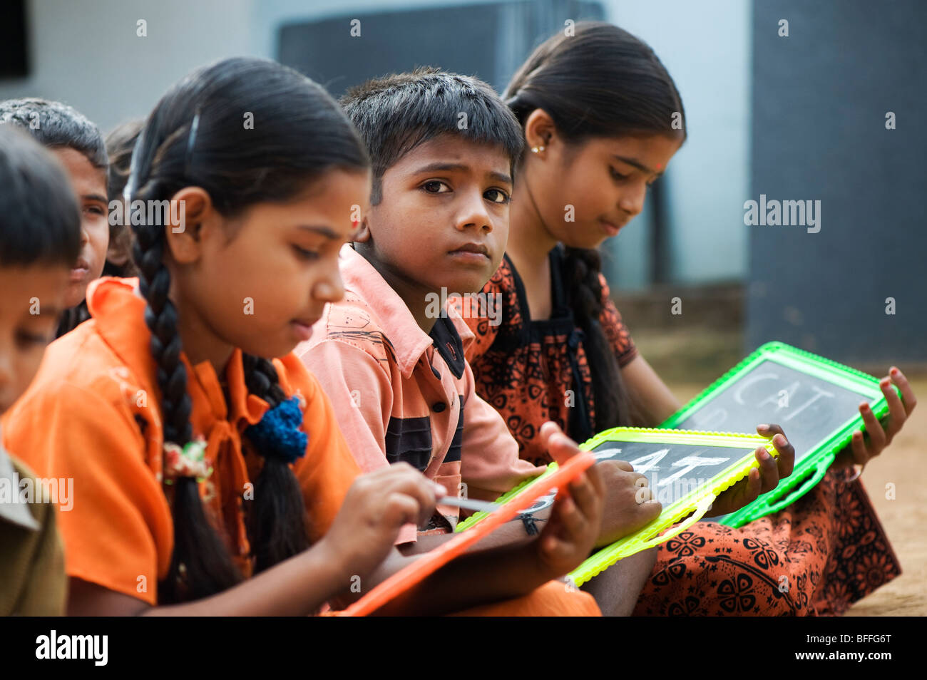 L'école indienne des enfants assis à l'extérieur de l'école écrit sur des tableaux noirs. L'Andhra Pradesh, Inde. Focus sélectif. Banque D'Images