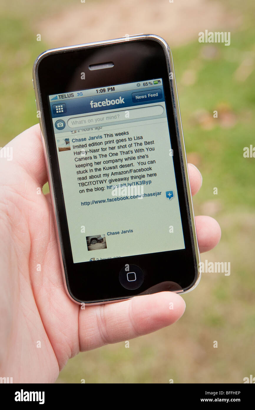 Un homme utilisez l'application Facebook sur un iPhone d'Apple Banque D'Images