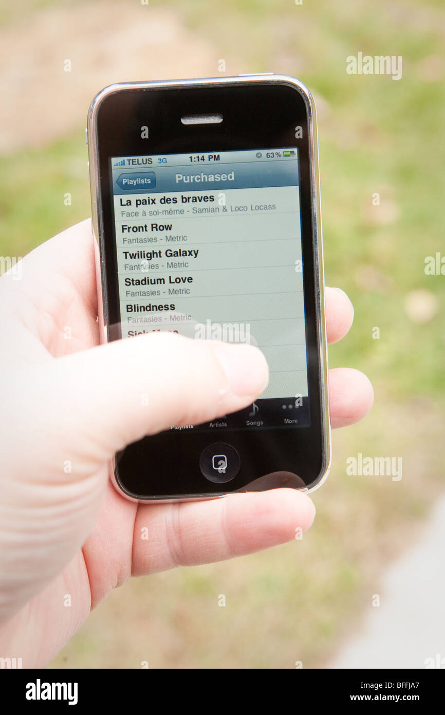 Un homme utiliser l'application MP3 sur un iPhone d'Apple. Banque D'Images