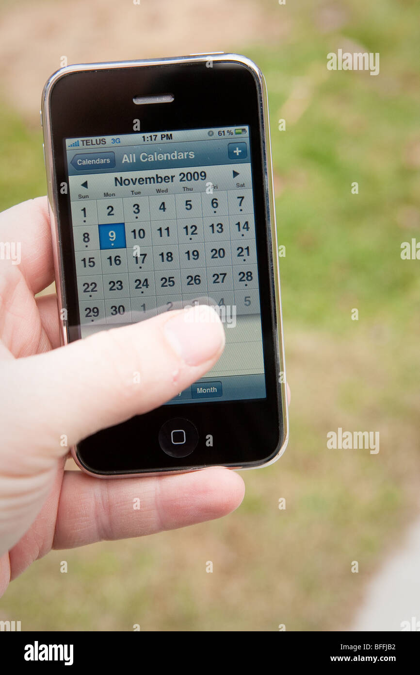 Un homme utilisez l'application de calendrier sur un iPhone d'Apple. Banque D'Images