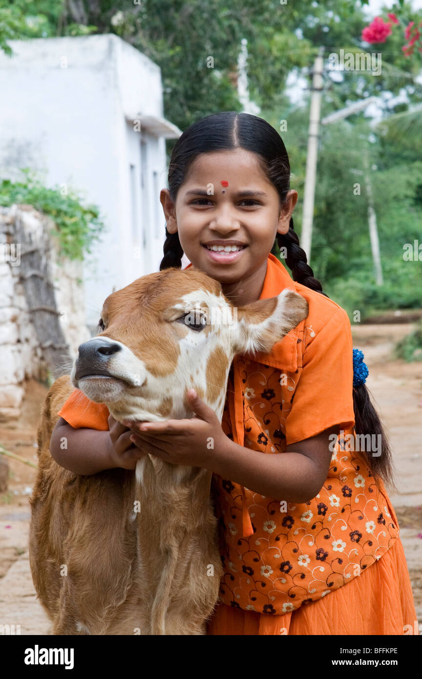 Jeune Indien village girl hugging un veau dans un village de l'Inde rurale. L'Andhra Pradesh, Inde Banque D'Images