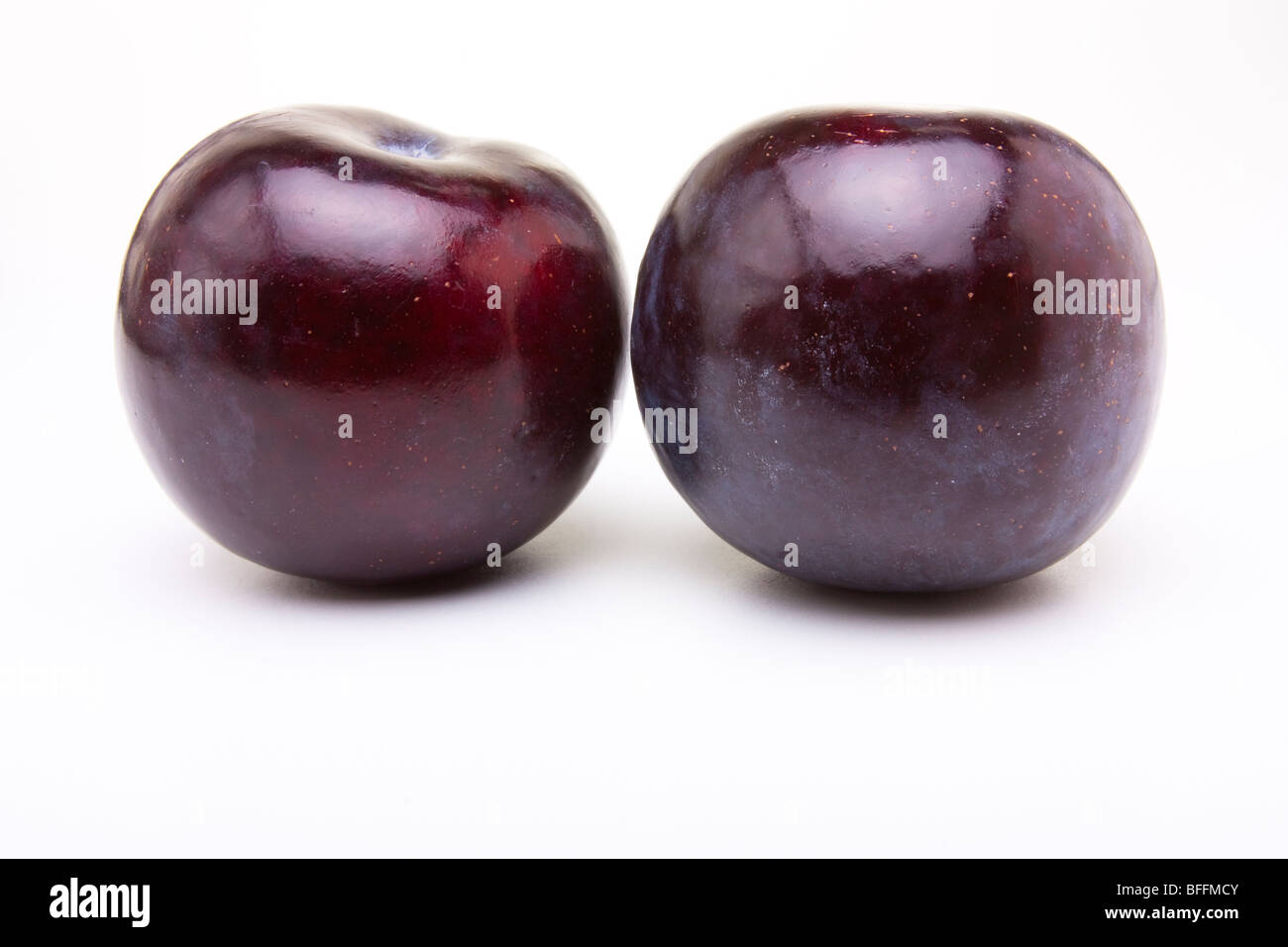 Prune pourpre brillant contre isolé sur fond blanc. Banque D'Images