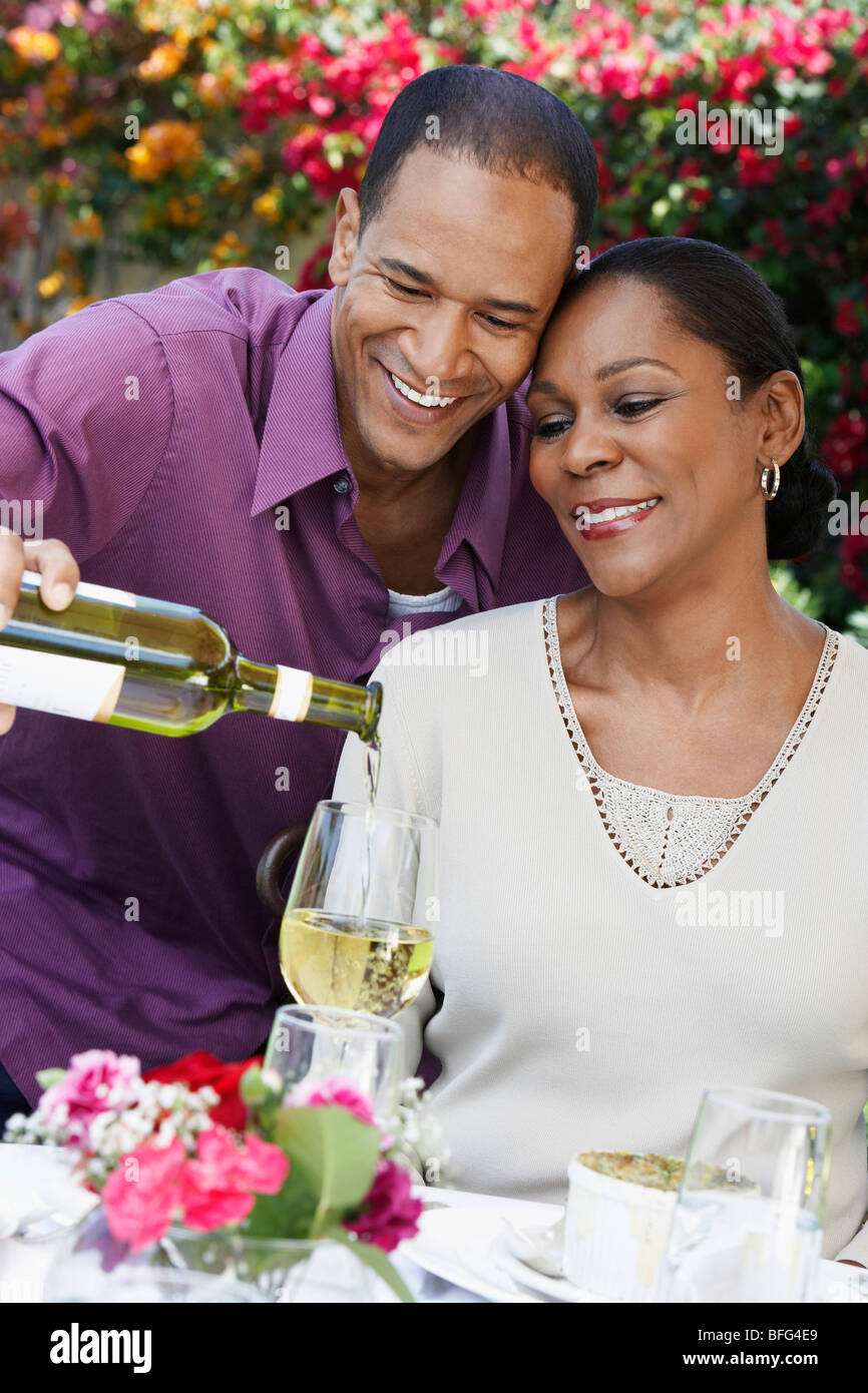 Couple d'âge moyen au vin partage outdoor table Banque D'Images