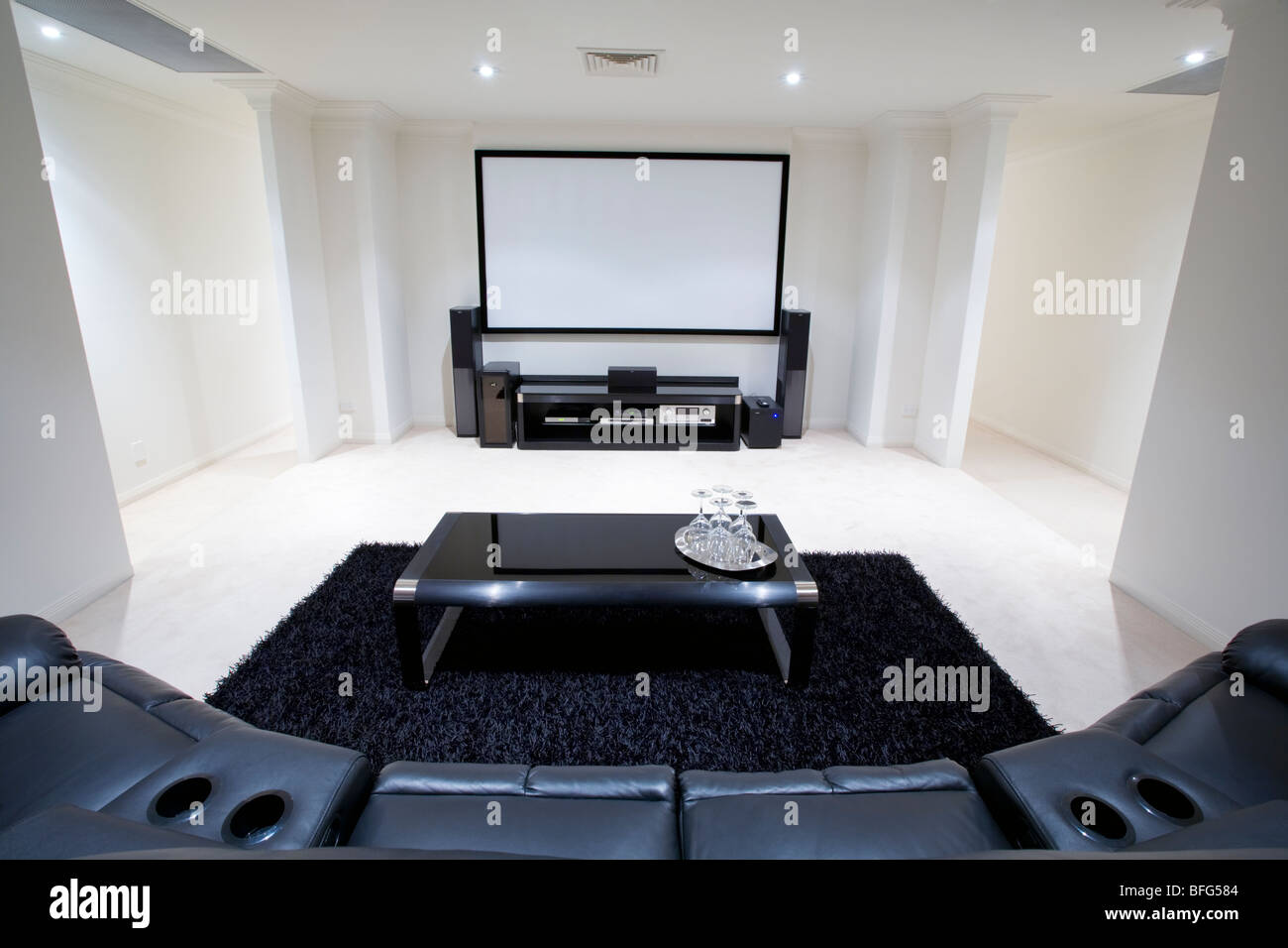 Salle de home cinéma avec un fauteuil inclinable en cuir noir, tapis noir  et une table avec des verres à vin Photo Stock - Alamy
