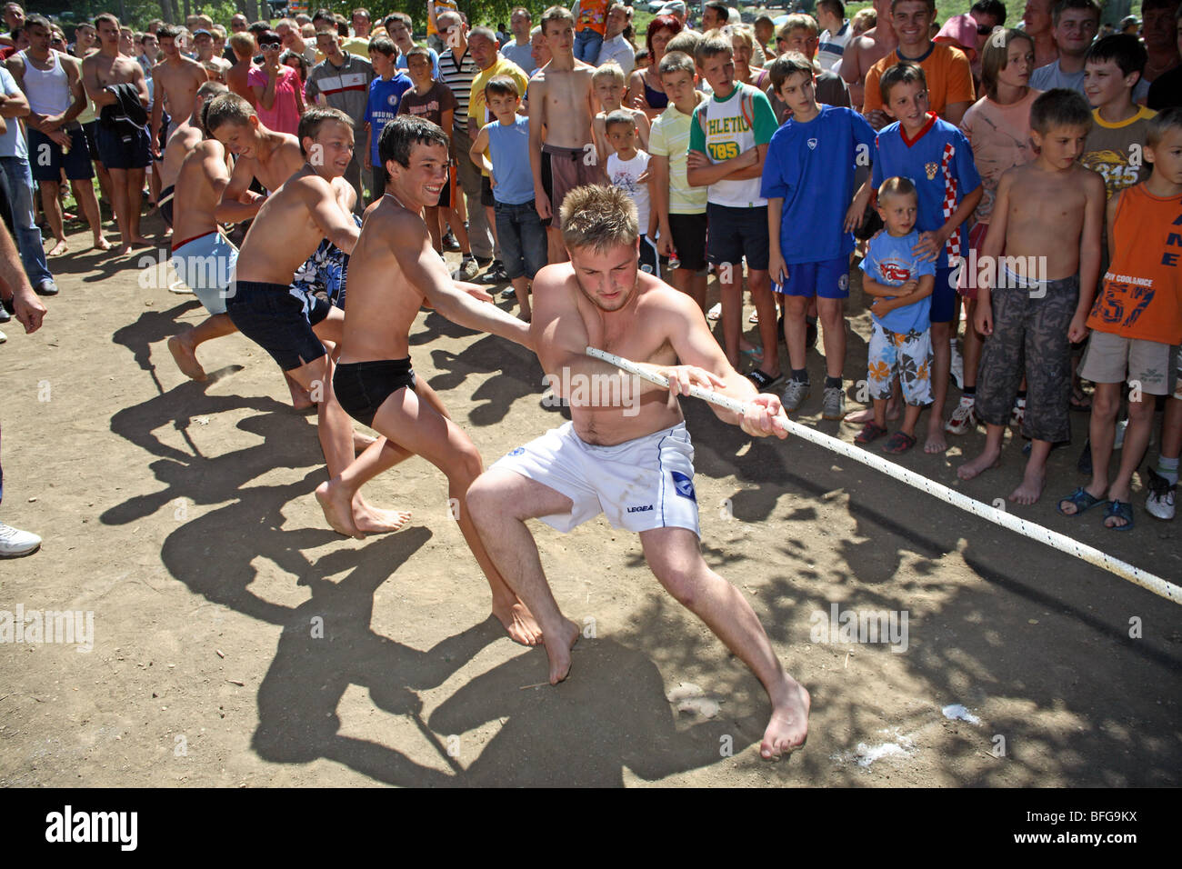 Une équipe de garçons corde tire sur une plage à un remorqueur de la guerre vu par la foule de spectateurs. Banque D'Images