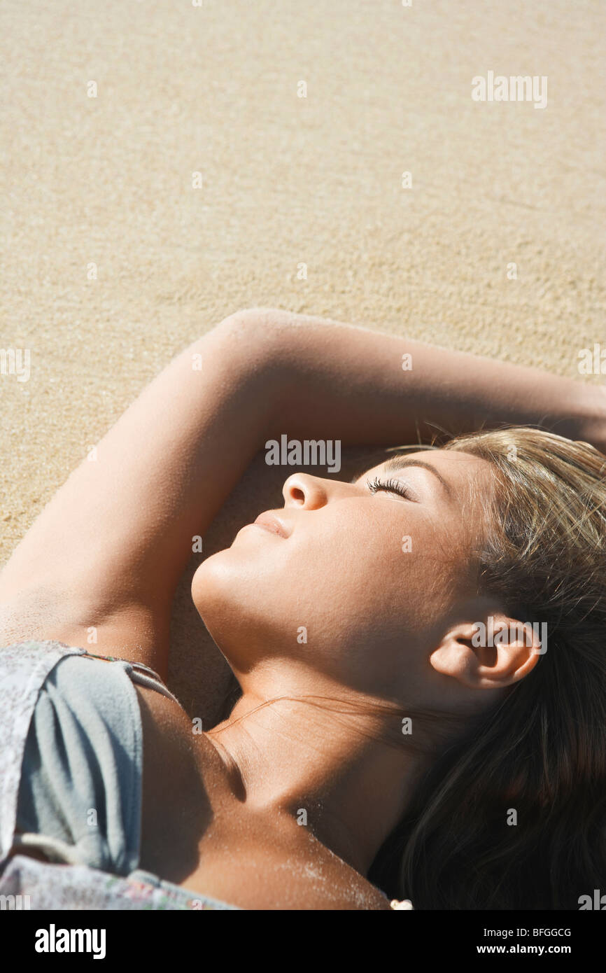 Young Woman Sunbathing on Beach Banque D'Images