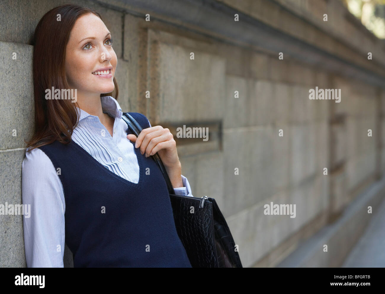 Young woman leaning against Wall street en Banque D'Images