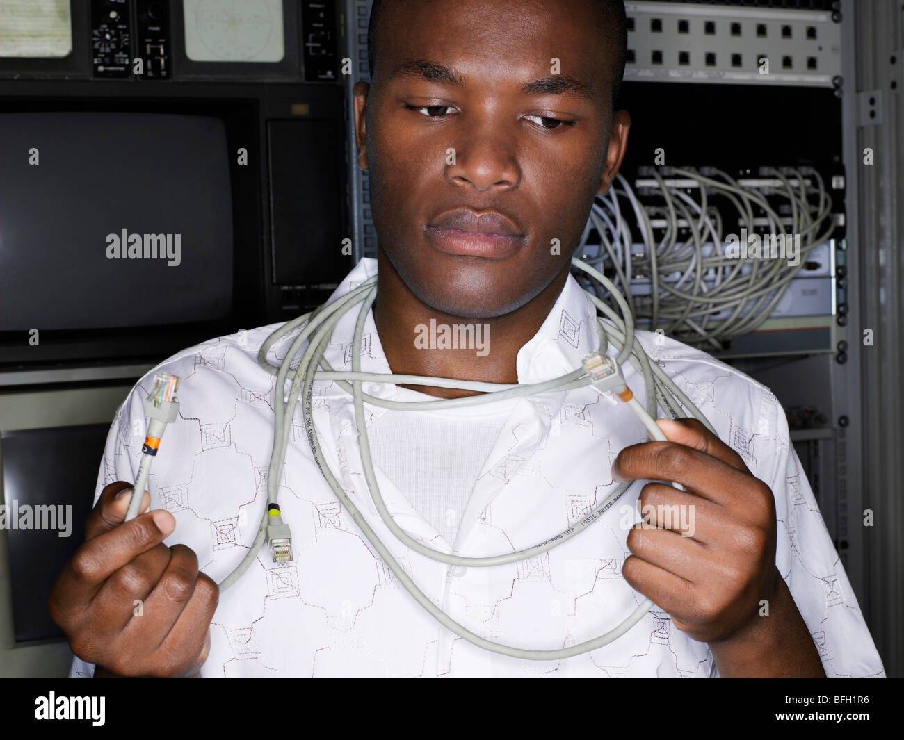 Jeune homme avec les câbles du réseau autour de cou, vue de face. Banque D'Images
