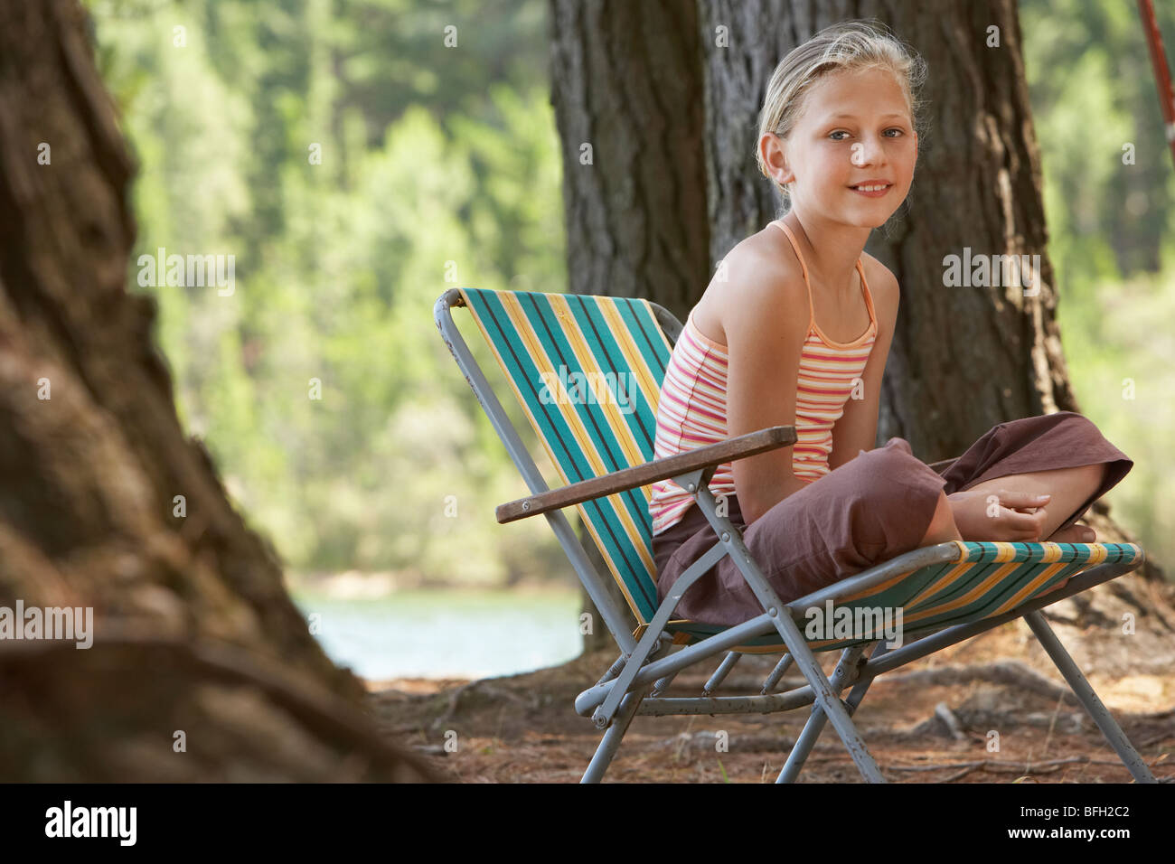 Fille assise sur une chaise longue dans la forêt Banque D'Images