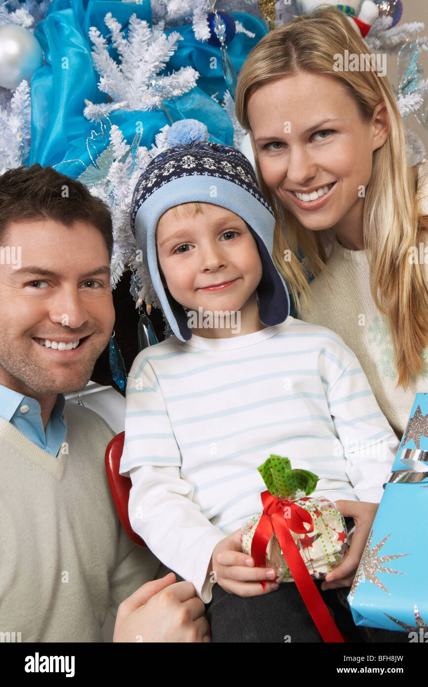 Couple avec son (5-6) holding present in front of Christmas Tree Banque D'Images