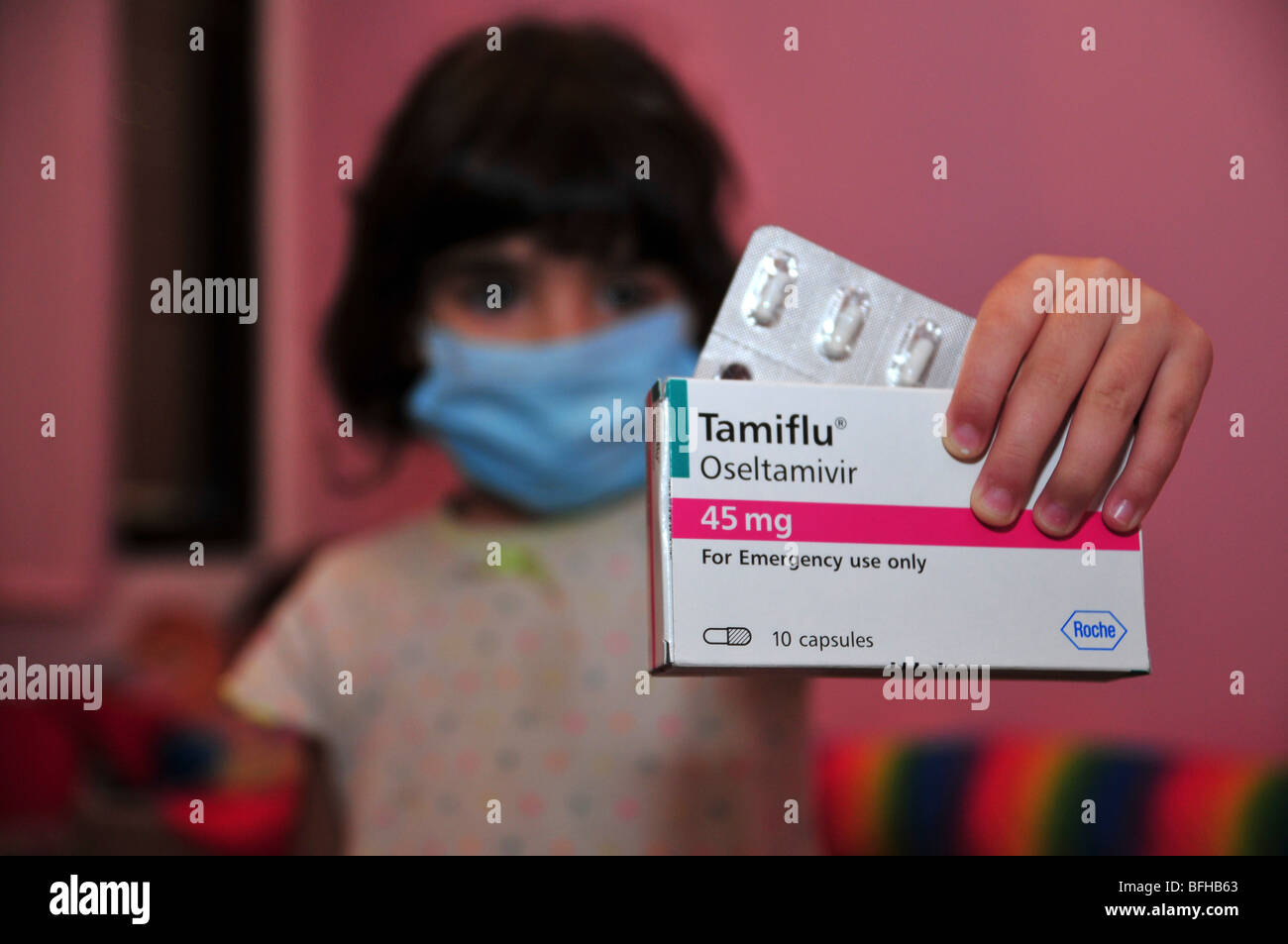 Une jeune fille porte un masque médical et est titulaire d'un lot de comprimés de Tamiflu contre la grippe porcine, le 30 octobre 2009. Banque D'Images