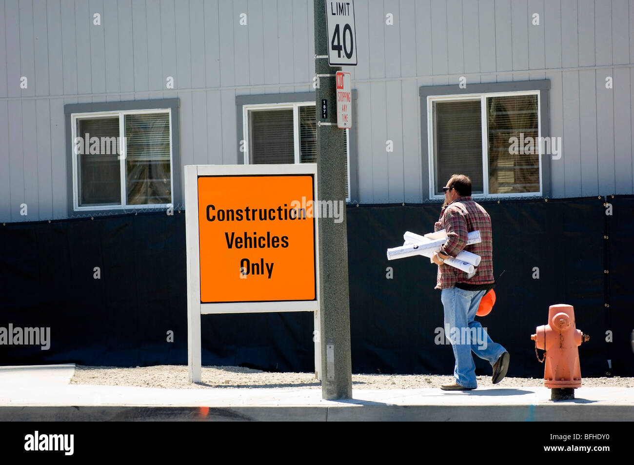 Ingénieur avec dessins entre dans une zone de construction. Banque D'Images