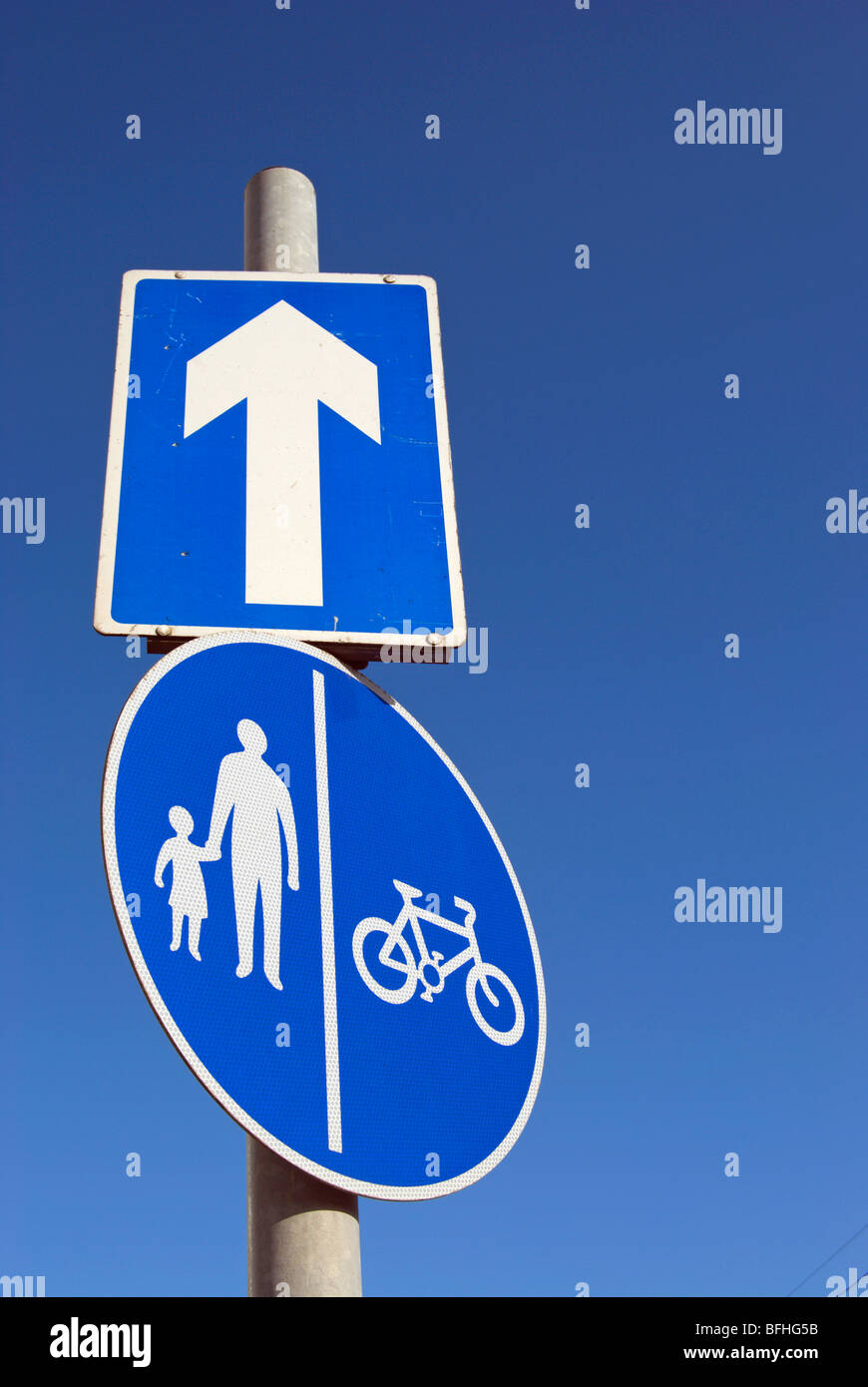 La signalisation routière indiquant une rue à sens unique, d'une flèche blanche, et des couloirs séparés pour les cyclistes et piétons Banque D'Images
