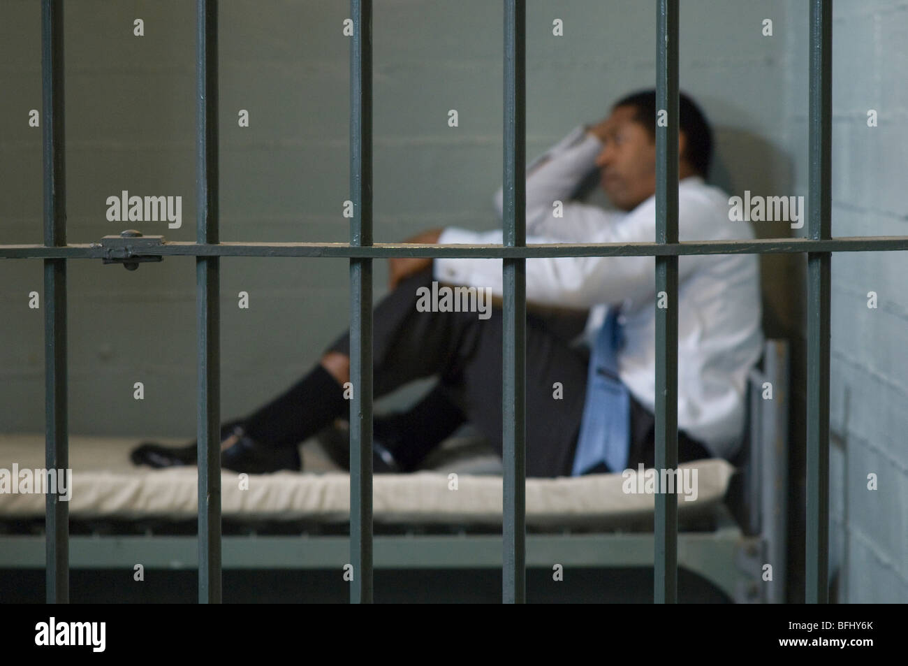 Man sitting on bed in prison cell Banque D'Images