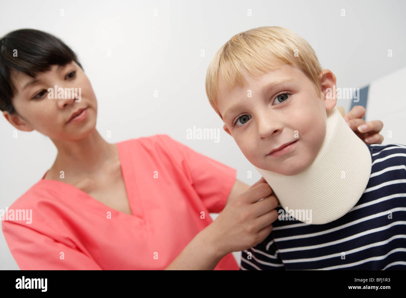 Nurse assisting boy wearing neck brace à l'hôpital Banque D'Images