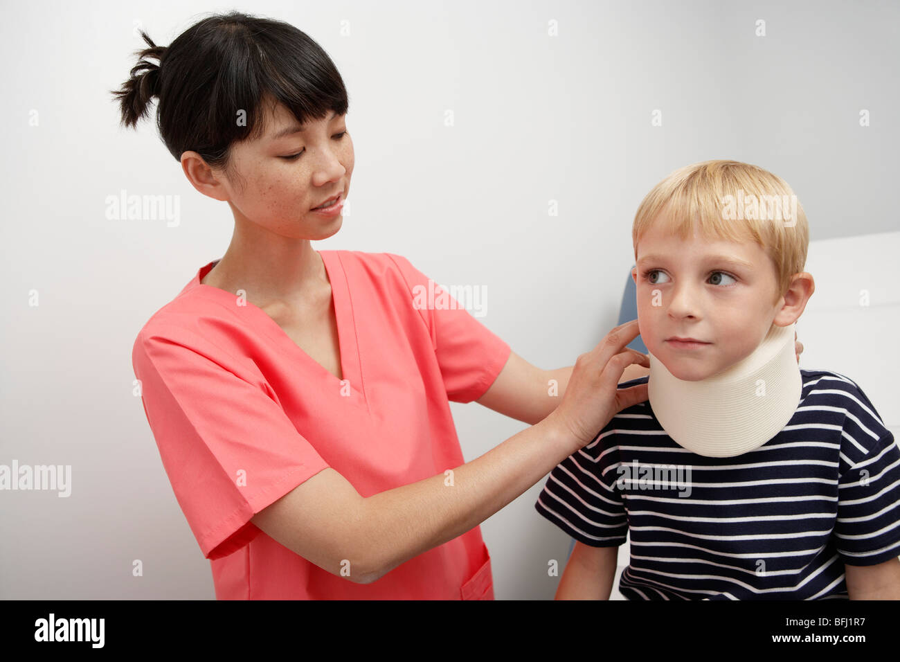 Nurse assisting boy wearing neck brace à l'hôpital Banque D'Images