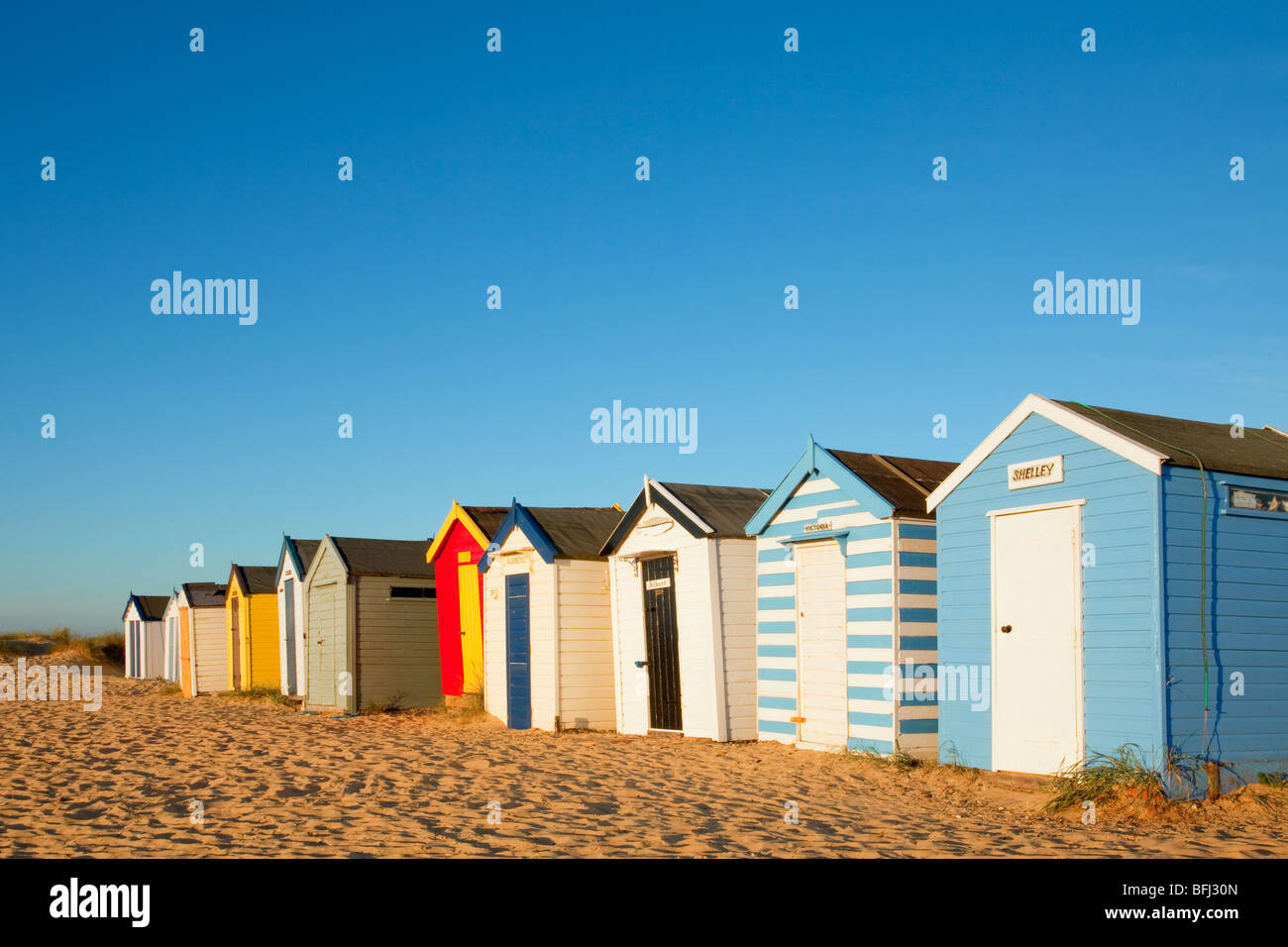 La célèbre plage de Southwold colorés abris contre un ciel bleu vif sur la côte du Suffolk Banque D'Images