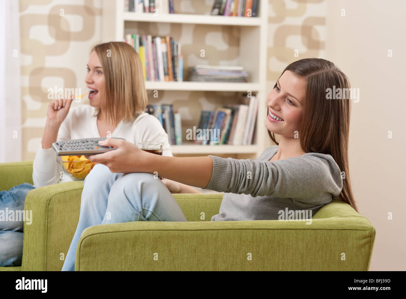 Deux étudiants - une adolescente à regarder la télévision et manger des chips dans un salon moderne Banque D'Images