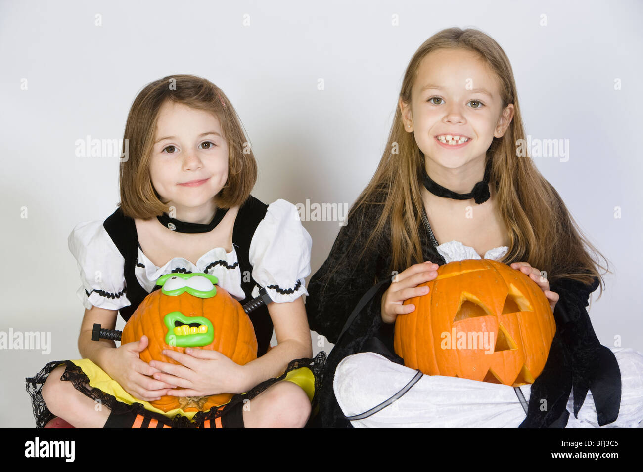 Portrait of girls (7-9) wearing Halloween costumes, avec jack-o-lanternes Banque D'Images