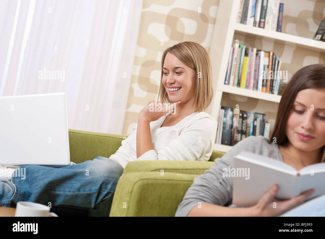 Deux étudiants - une adolescente étudie avec ordinateur portable et réservez in modern living room Banque D'Images