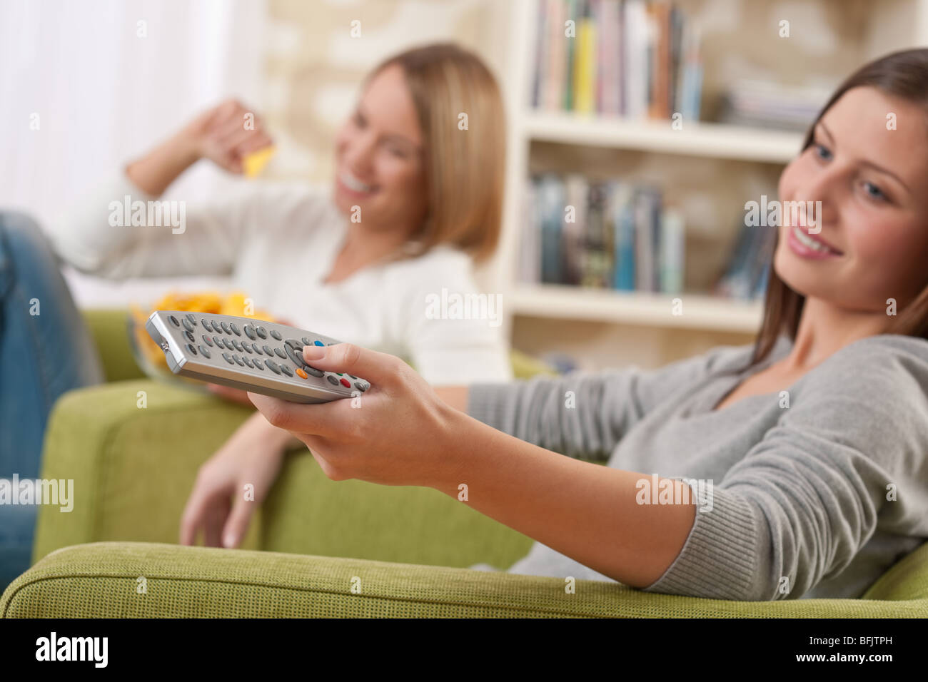 - Deux étudiants female adolescent regardant la télévision dans salon moderne, l'accent sur le contrôle à distance Banque D'Images