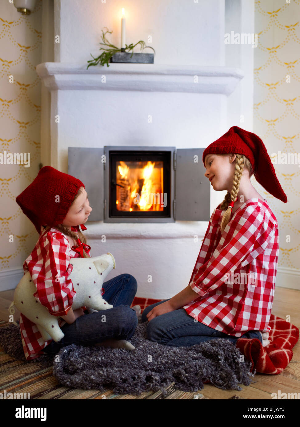 Soeurs assis en face d'une cheminée à Noël. Banque D'Images