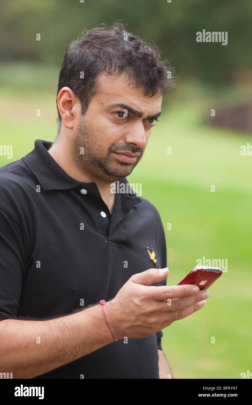 Un homme asiatique contrôler des distances sur le parcours avec un i phone tout en jouant au golf Banque D'Images