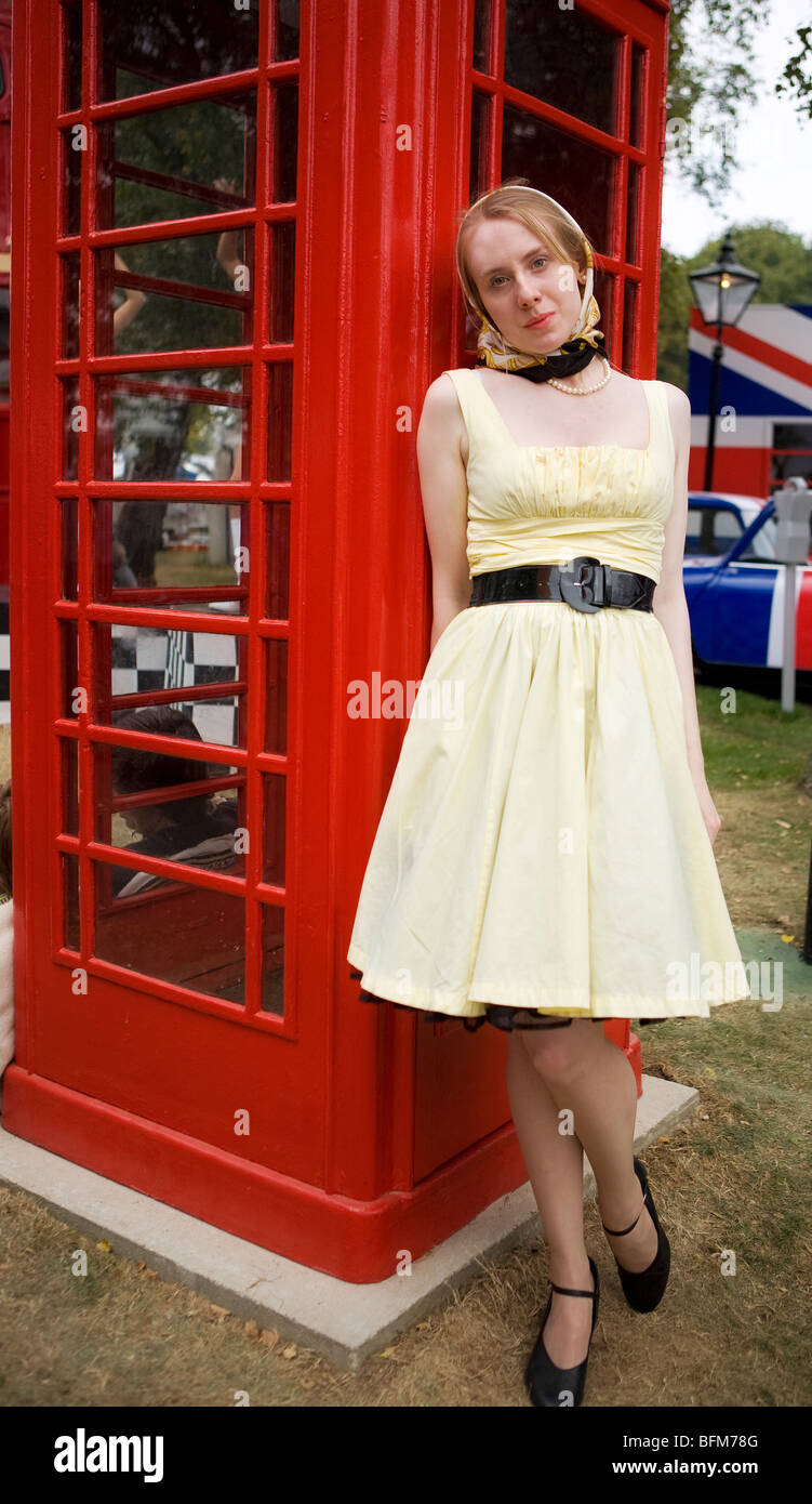 Jeune fille vêtue de costume des années 60 se posant devant la boîte de téléphone rouge à Goodwood Revival, Chichester, West Sussex, Angleterre. Banque D'Images