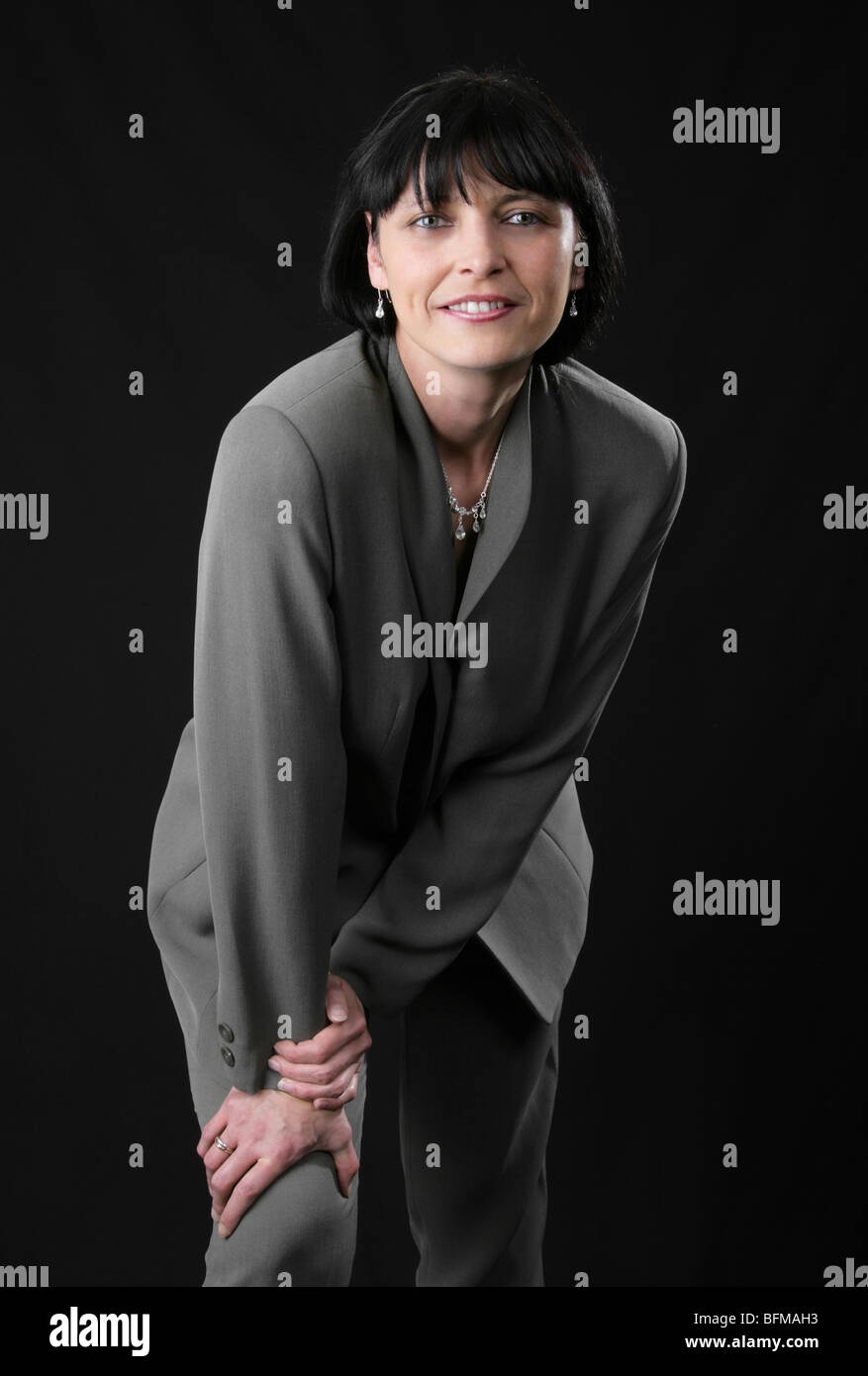 Portrait d'une femme de race blanche aux cheveux noirs portant un costume gris Banque D'Images