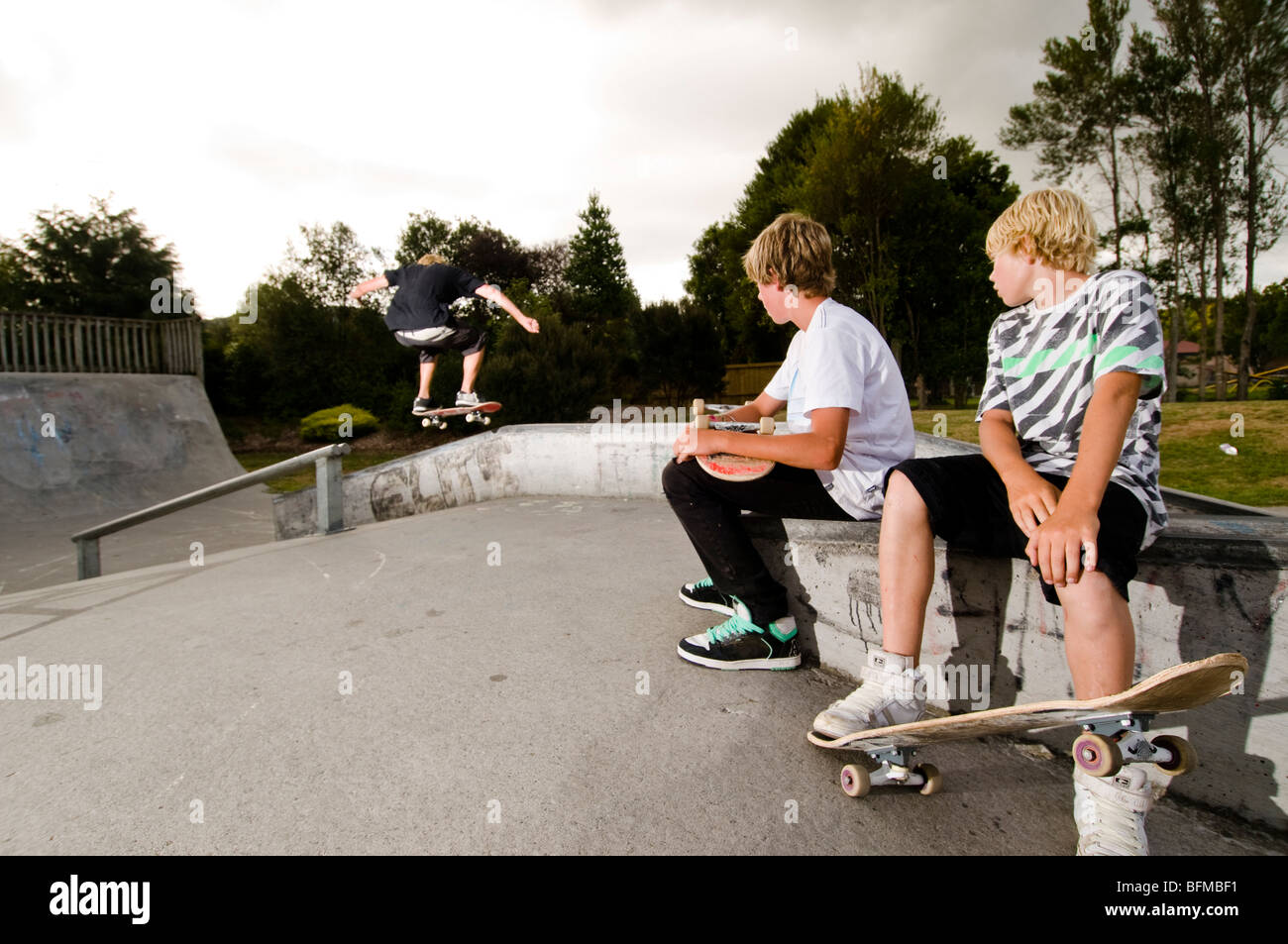 3 garçons faisant des tours dans le skate park avec soleil couchant,  Nouvelle-Zélande Photo Stock - Alamy