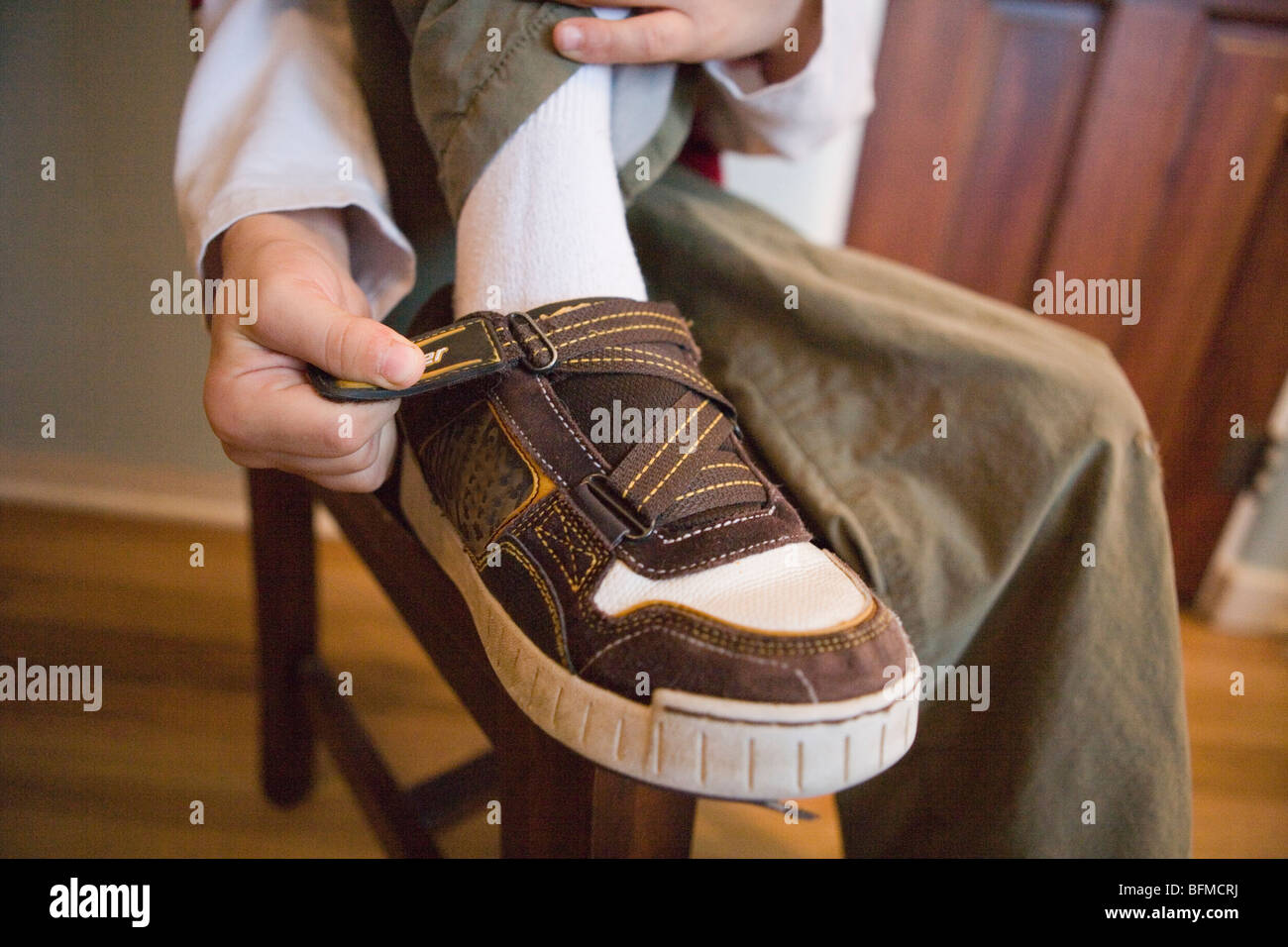 Portrait d'un enfant de mettre ses baskets à l'aide d'une sangle velcro, s'habiller Banque D'Images