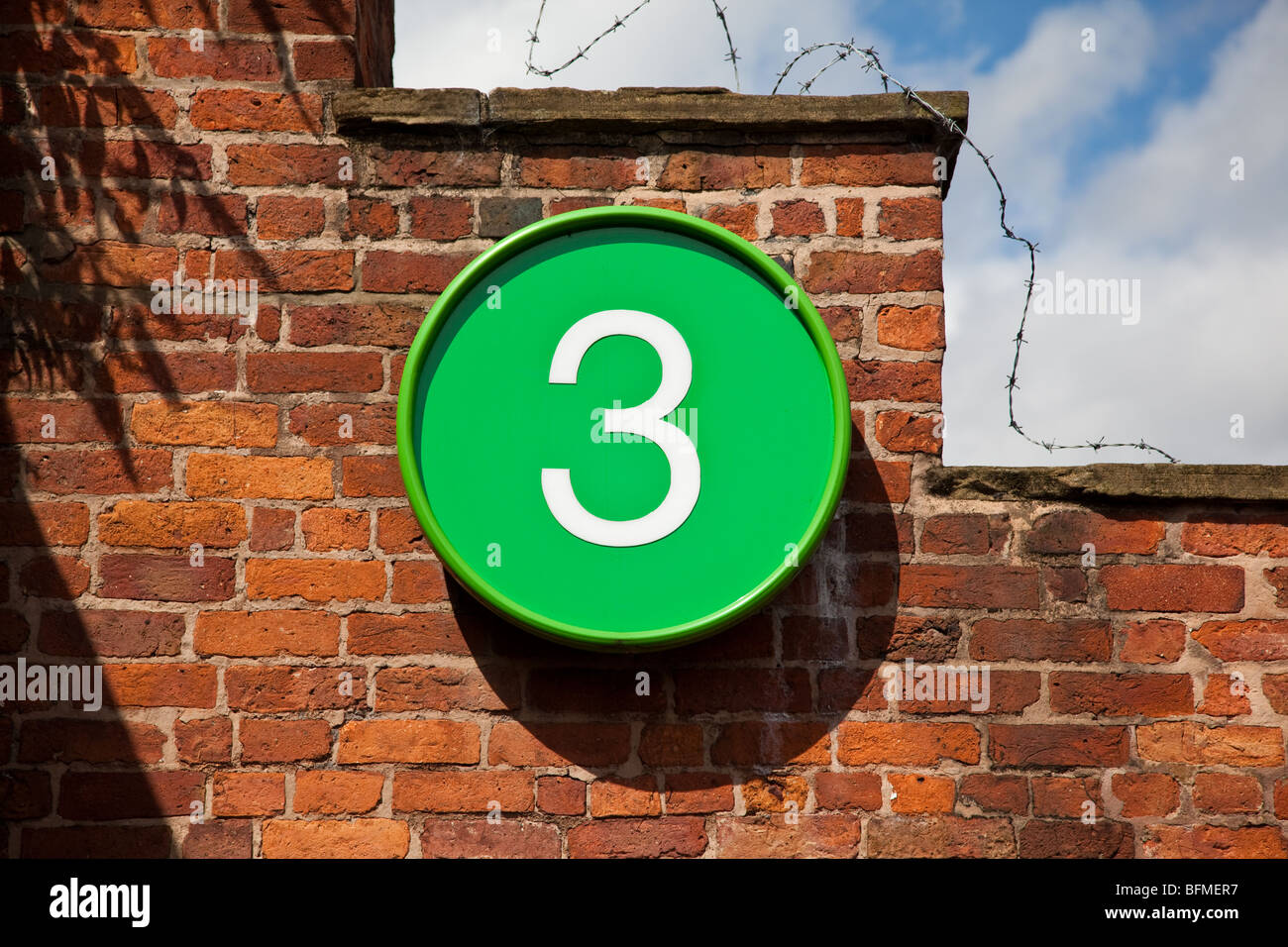 Numéro 3 en blanc sur cercle vert sur mur de brique Banque D'Images