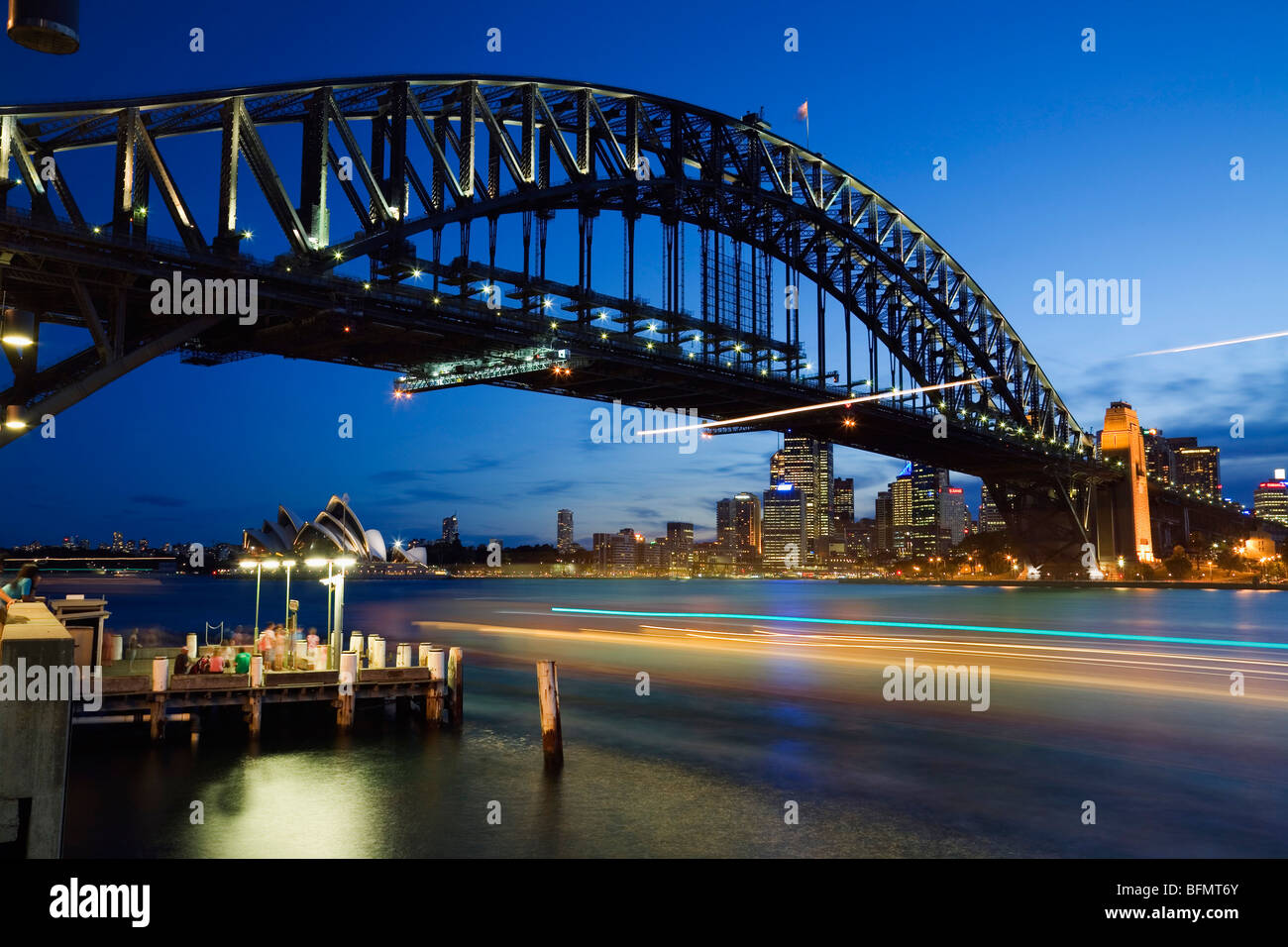 L'Australie, New South Wales, Sydney. Les sentiers de la lumière d'un ferry sur le port de Sydney, avec le Harbour Bridge et l'Opéra. Banque D'Images