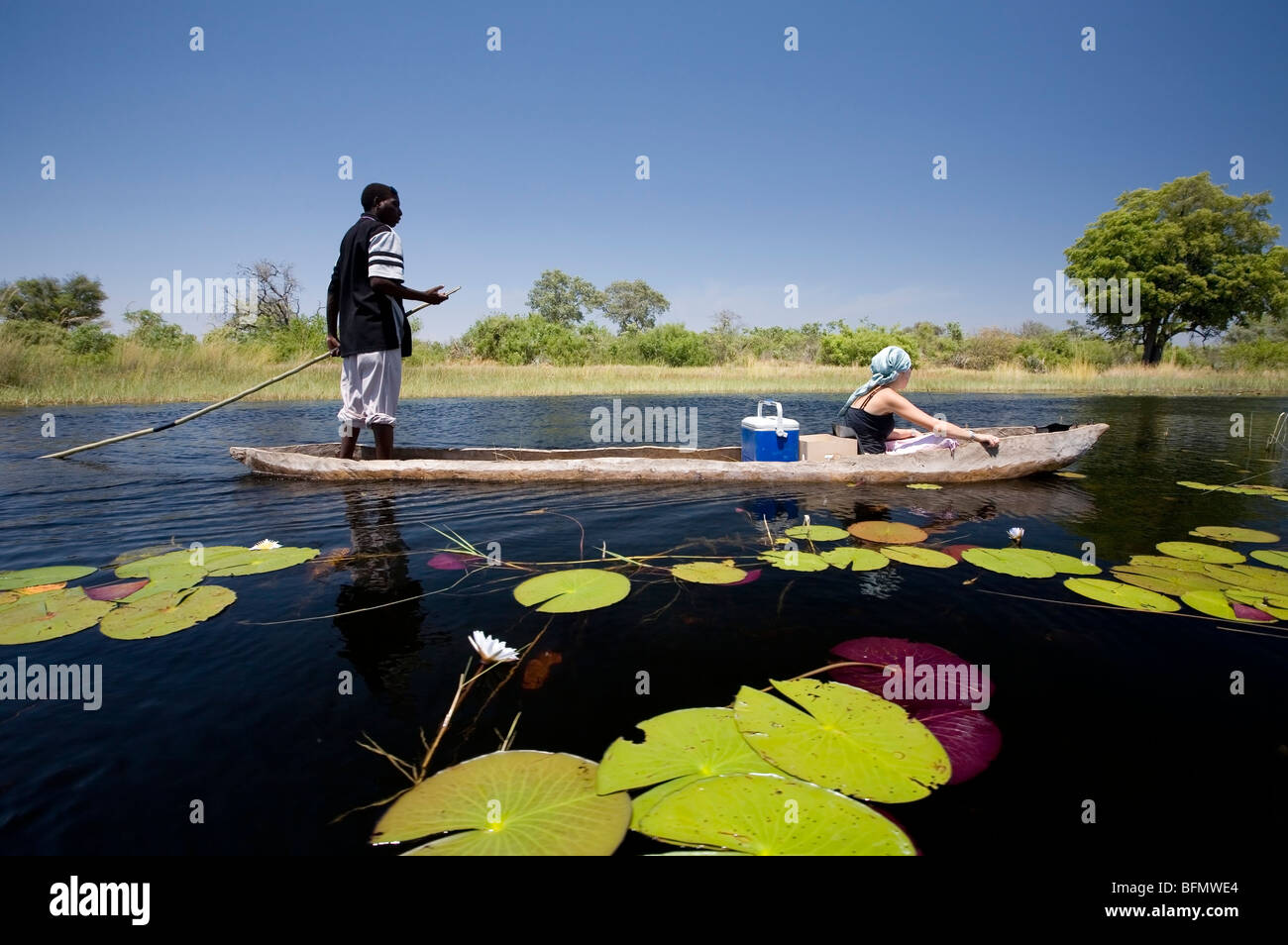 Le Botswana, le delta de l'Okavango. Un guide local plates un mokoro à travers les canaux du Delta de l'Okavango Banque D'Images