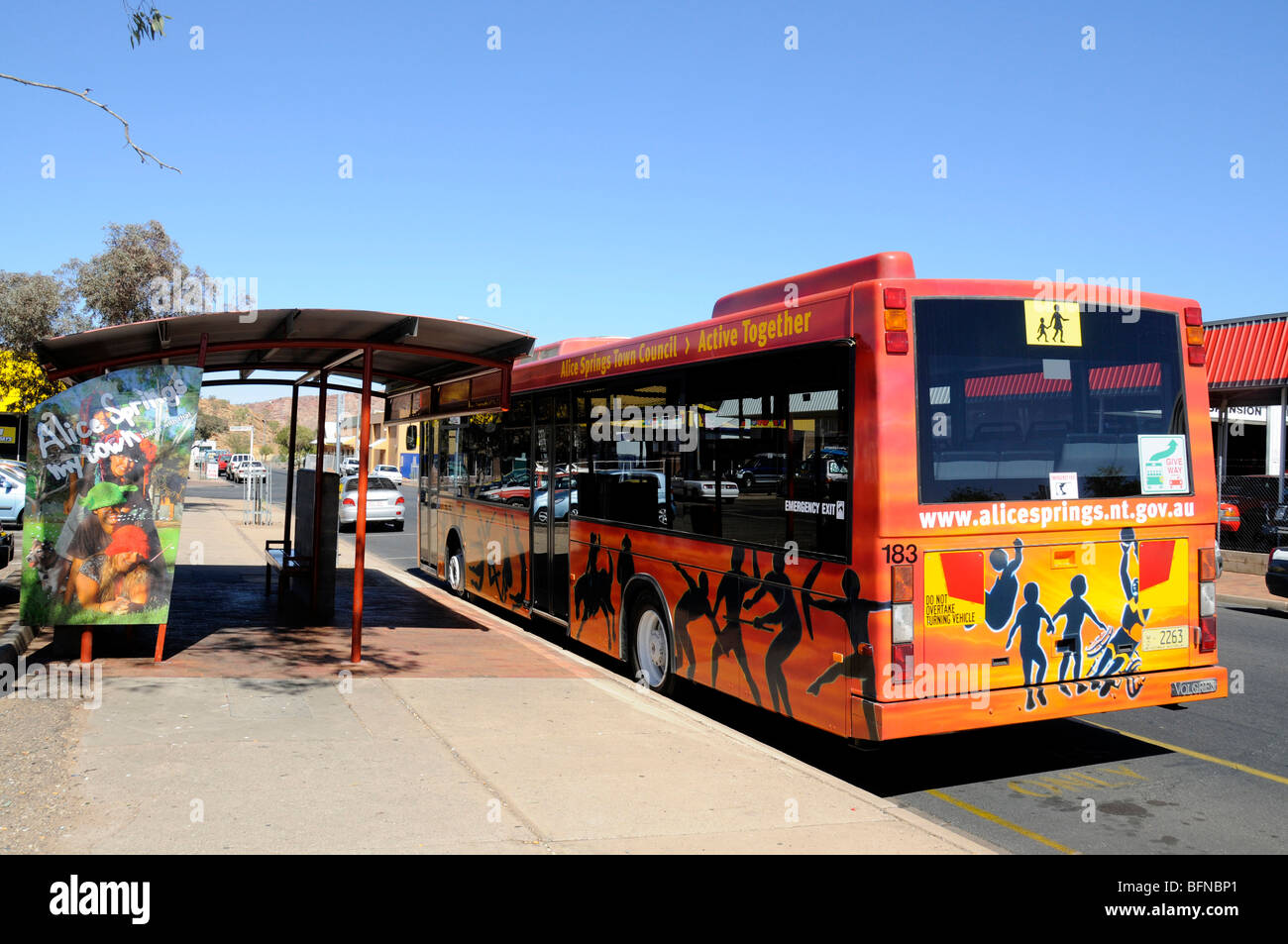 Un bus des transports publics peints dans l'art autochtone parqué dans un arrêt de bus à Alice Springs, Australie Banque D'Images